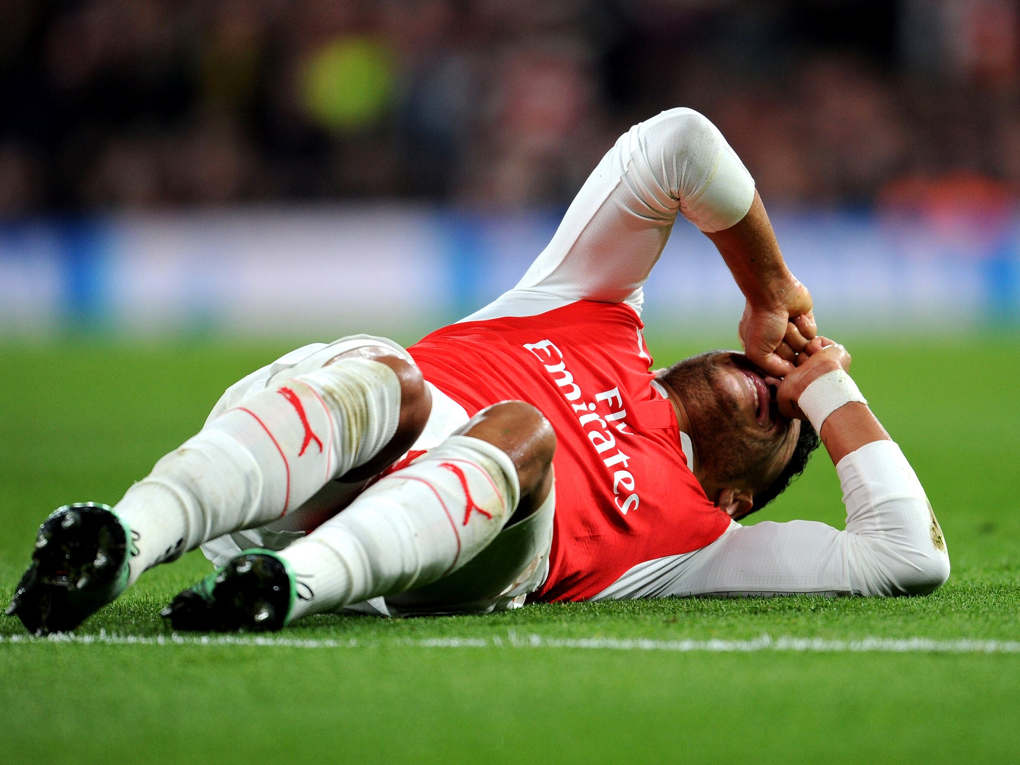 Alex Oxlade-Chamberlain grimaces after suffering the injury against Barcelona