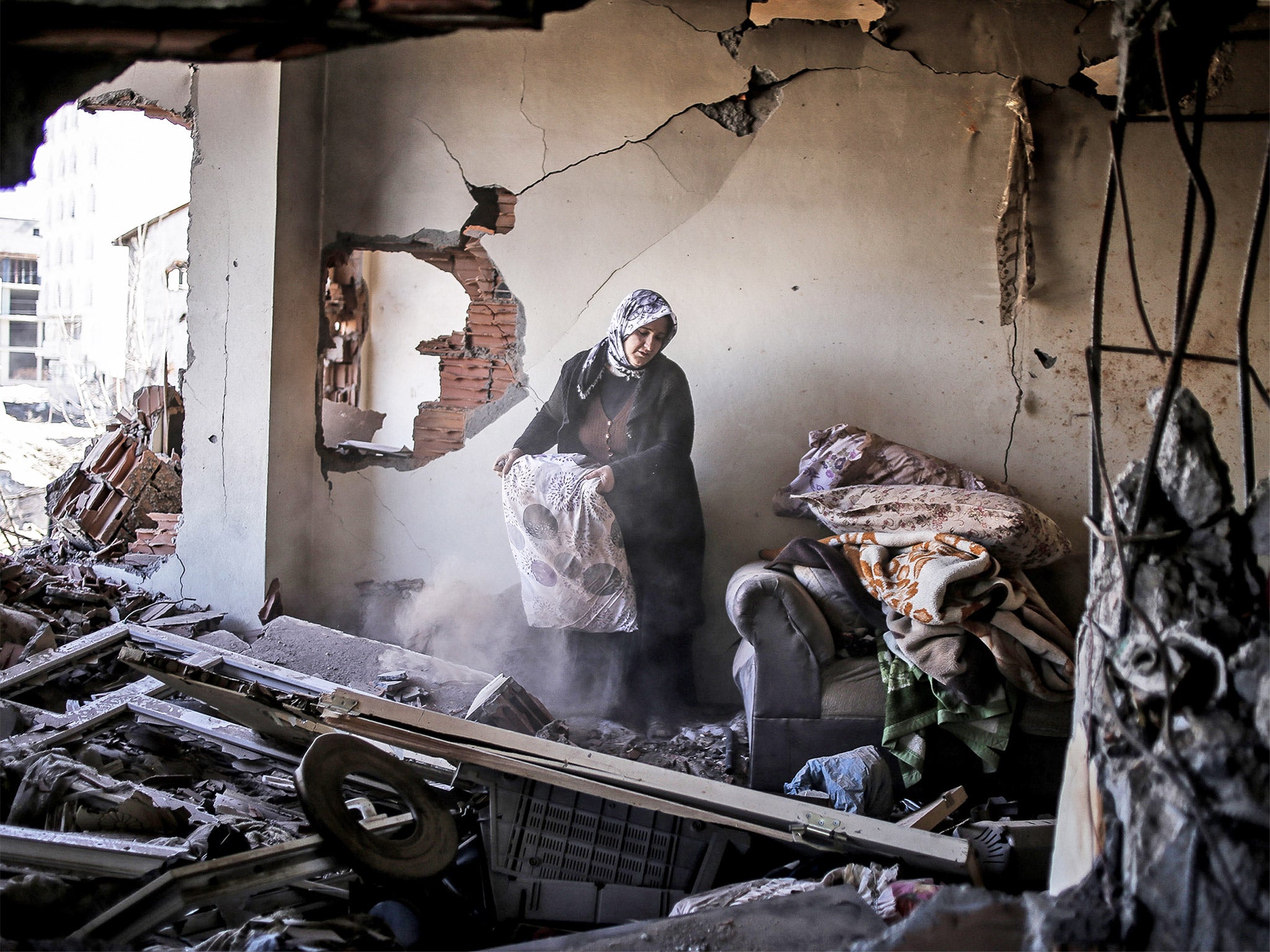 A woman inspects her belongings in her ruined home in Cizre. Turkish authorities have scaled down a 24-hour curfew imposed on the mainly Kurdish town