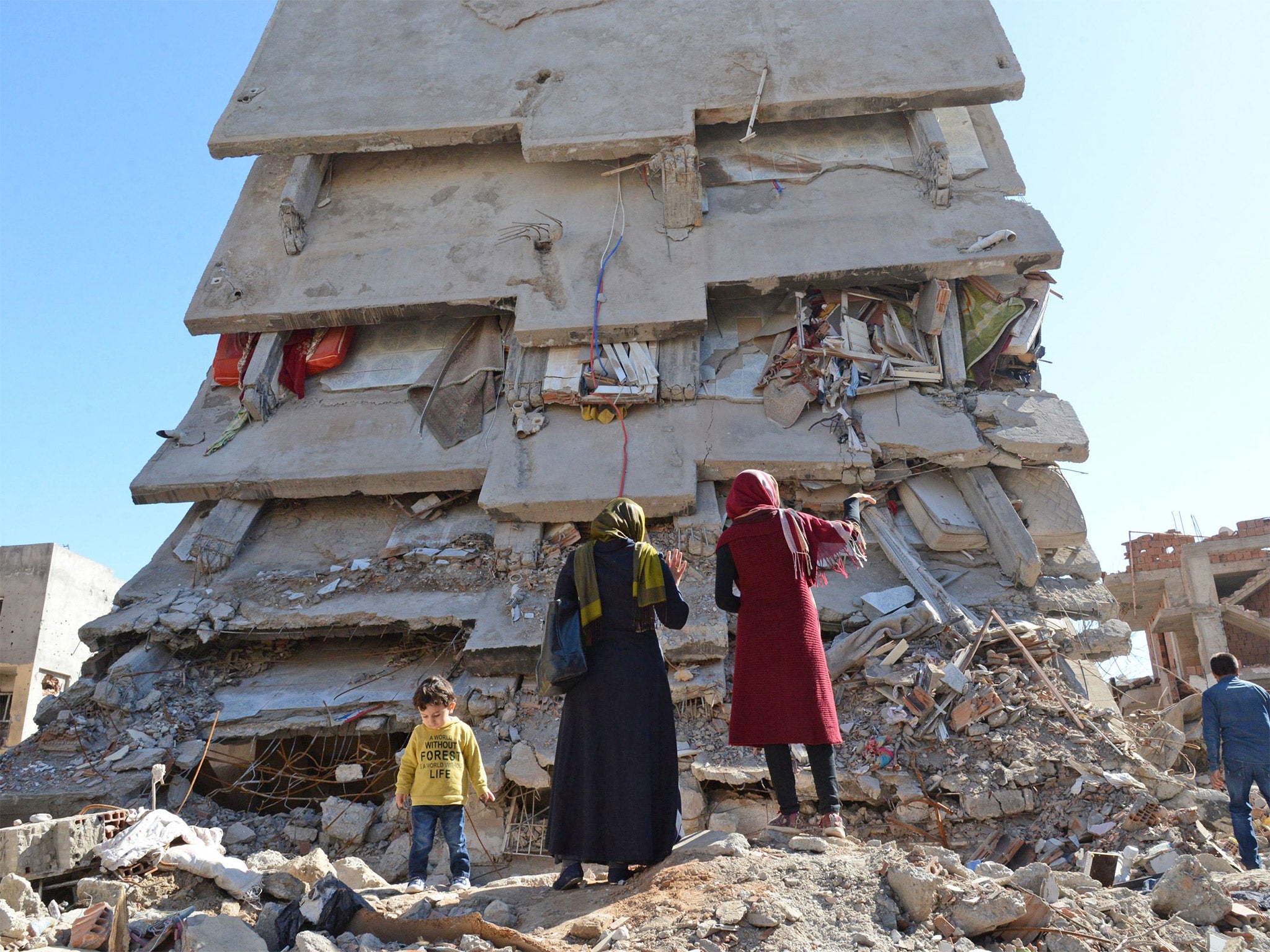 A family stands among the rubble of damaged buildings following heavy fighting in Cizre