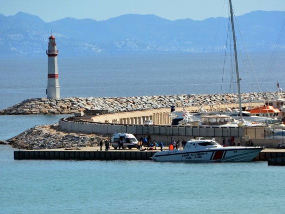 A Turkish Coast Guard boat and medics are seen with rescued migrants at the port of Didim, Turkey AP