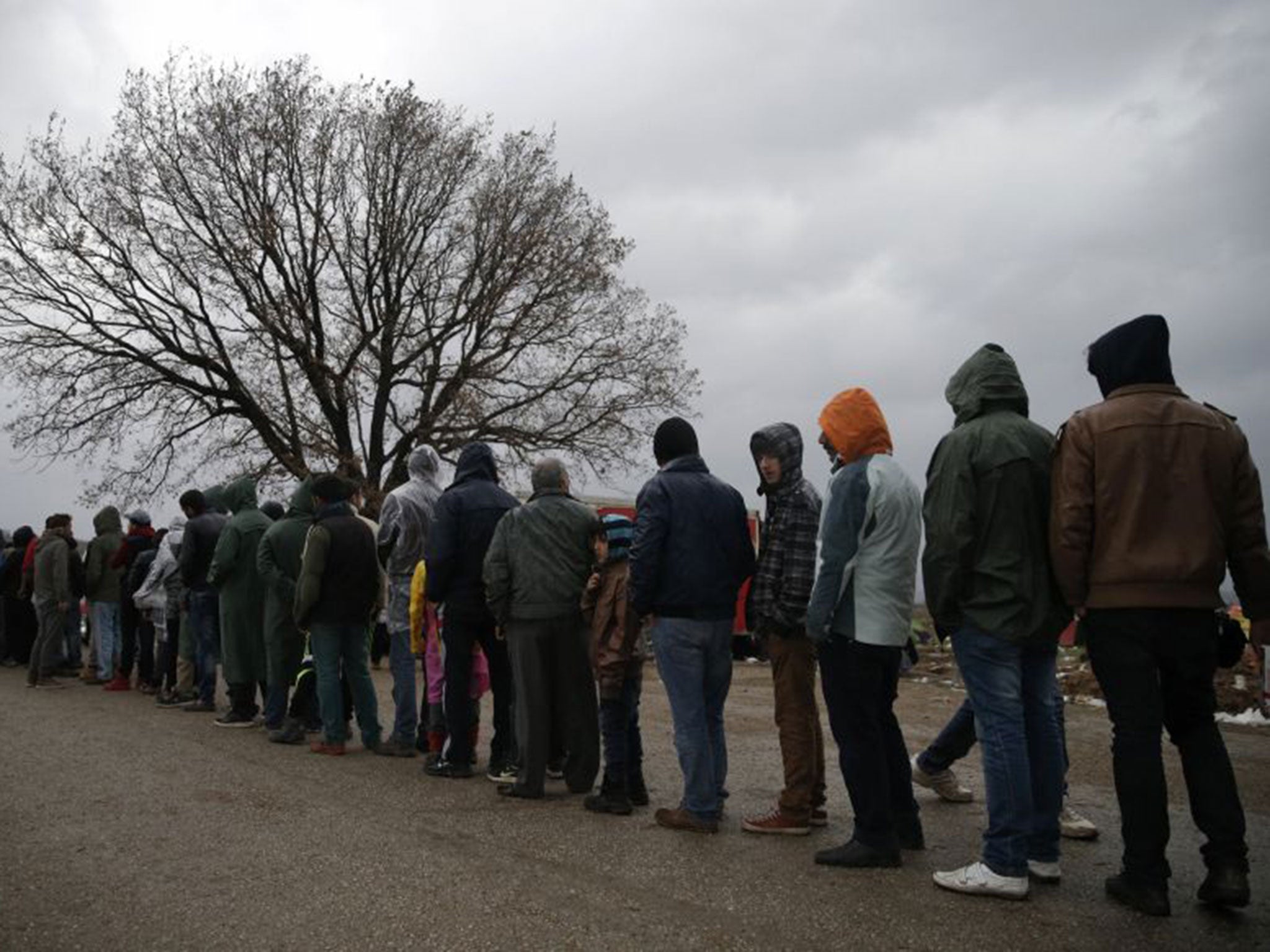 Migrant men queue for food at a makeshift camp near the village of Idomeni, Greece, as they wait to cross the Greek-Macedonian border