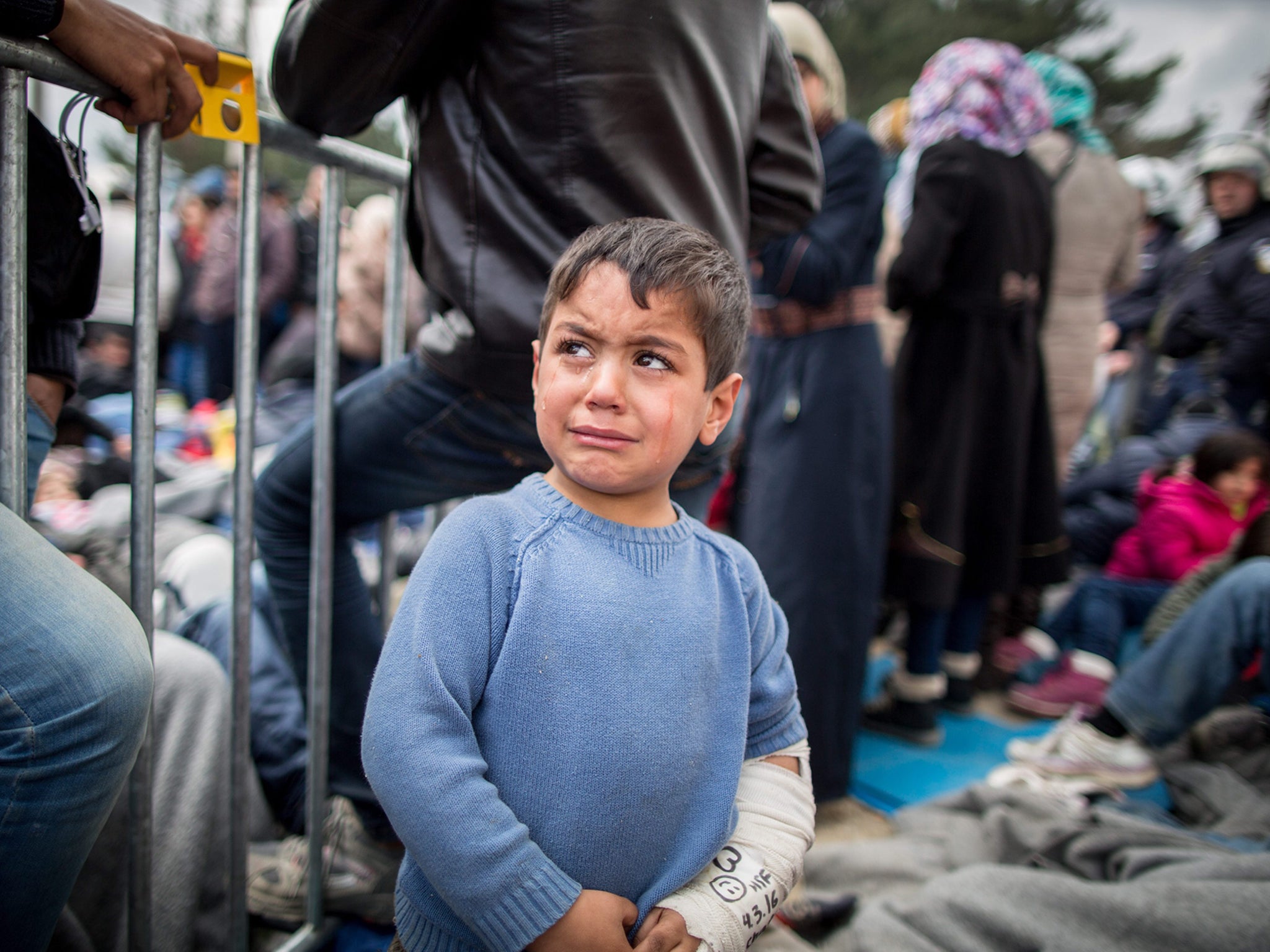 A refugee boy cries in front of the border gate in the refugee camp at the Greek-Macedonian border near Idomeni, Greece