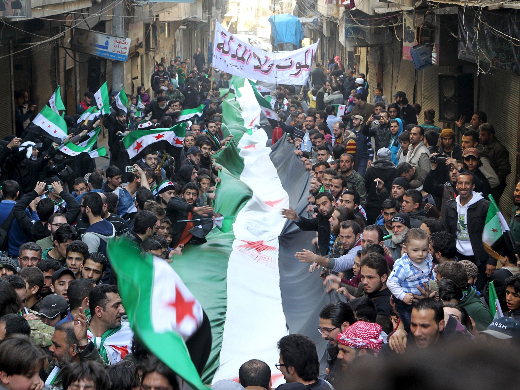 Protesters carry a Free Syrian Army flags during an anti-government protest in the al-Sukari neighborhood of Aleppo, Syria, March 11, 2016.