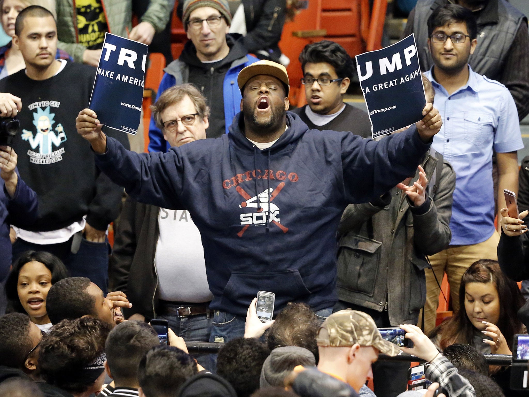 A protester holds up a ripped campaign sign for Republican presidential candidate Donald Trump before a rally on the campus of the University of Illinois-Chicago