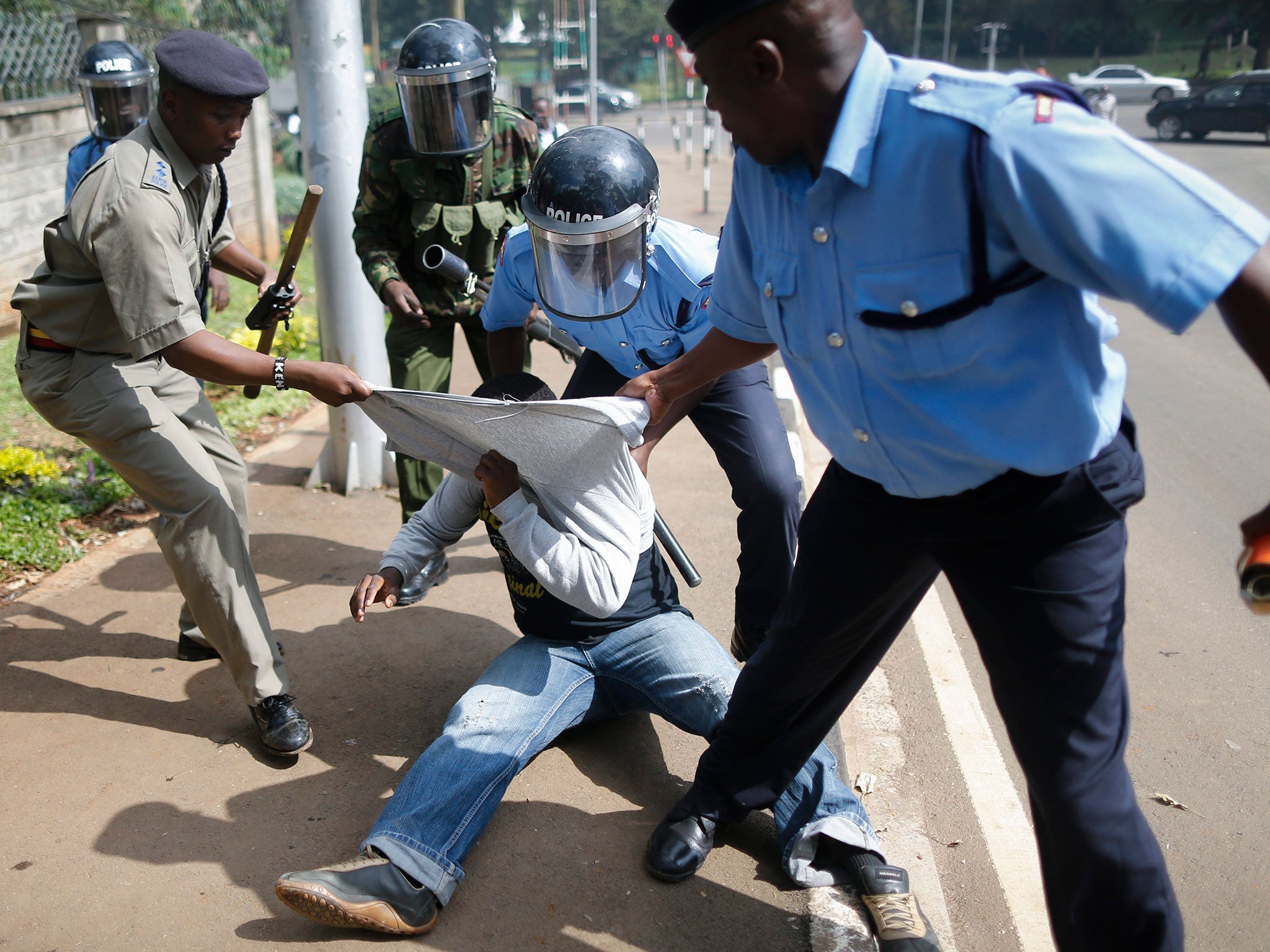 An activist is detained by police officers during a demonstration against corruption in central Nairobi