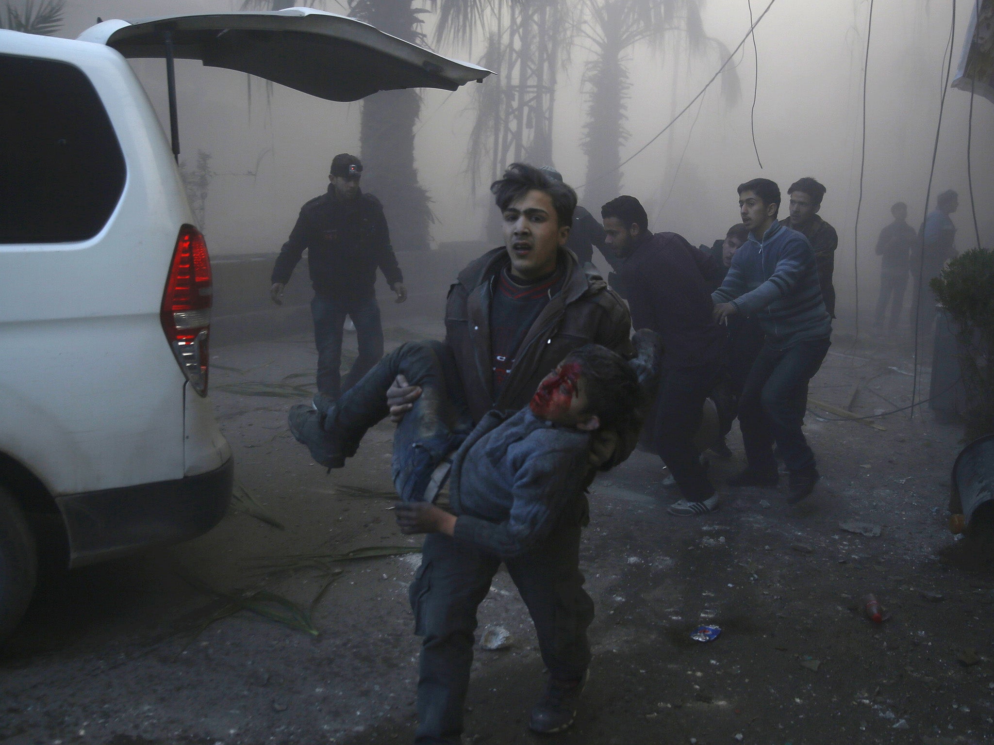 A Syrian boy carrying another injured boy away from the scene of a Russian air strike in Damascus in December 2015