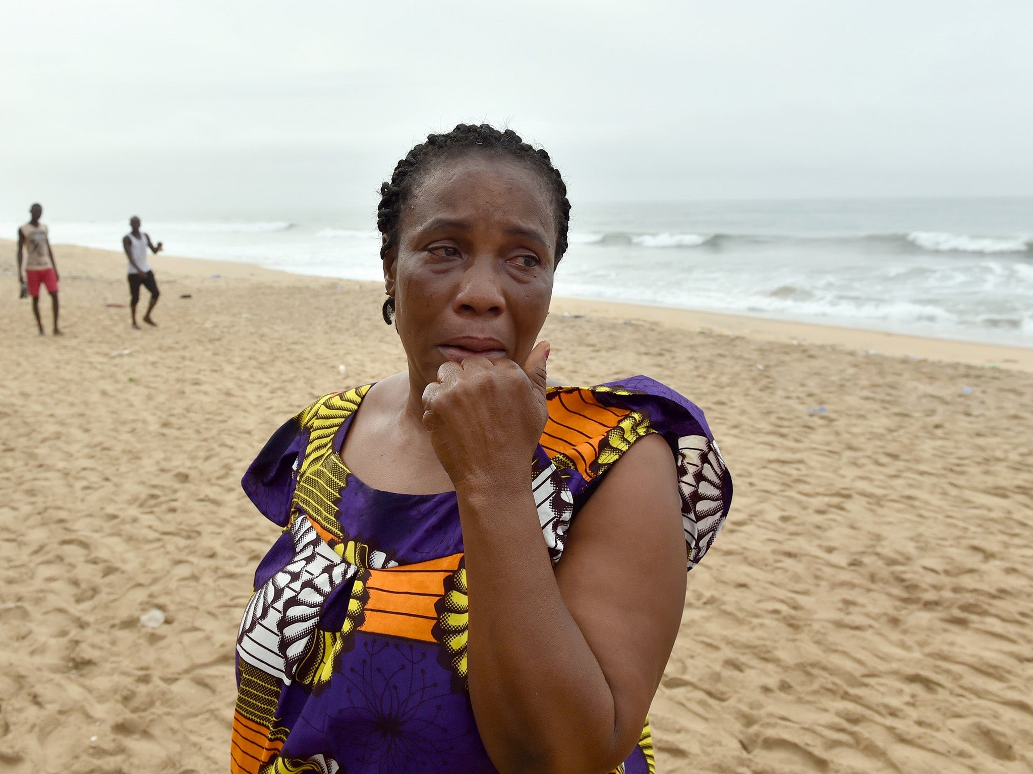 A woman weeps as she looks for her son on the Ivorian beach where the gunmen attacked