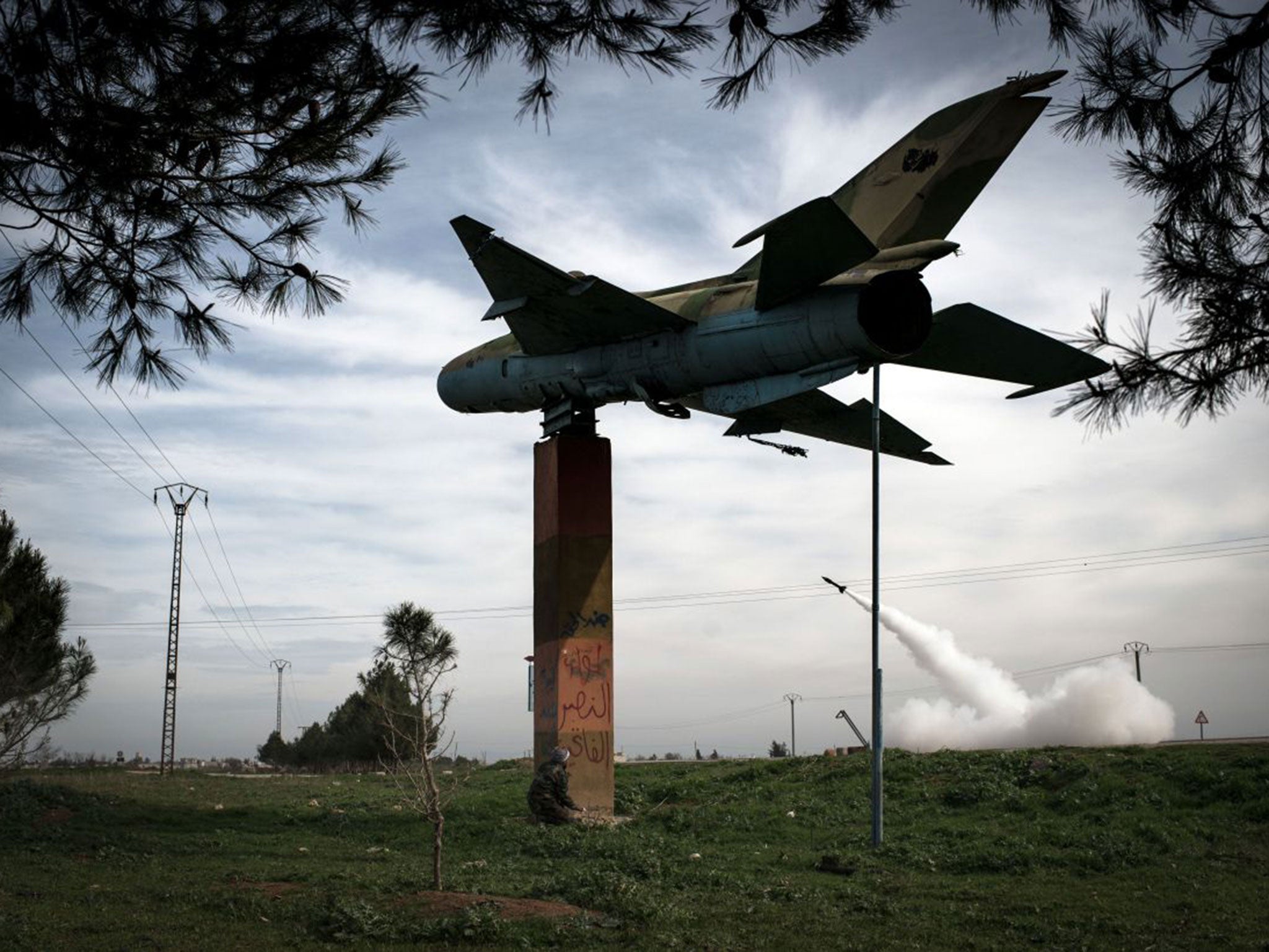 A man shelters beneath the gate guardian at Kwiriss airport in Al-Bab as rebels fire rockets at regime forces in February 2013