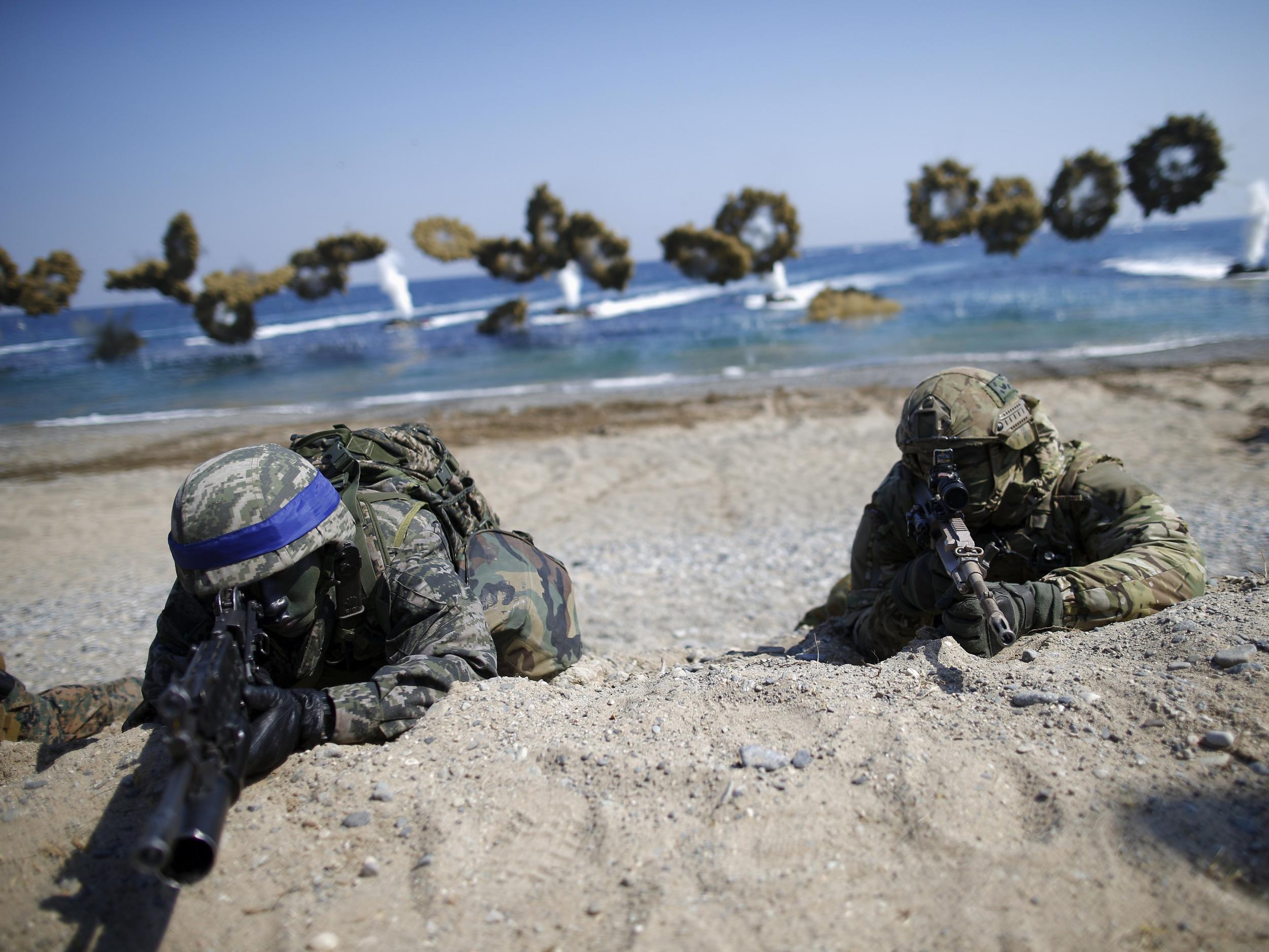 A South Korean and a US Marine take positions as amphibious assault vehicles of the South Korean Marine Corps fire smoke bombs during a US-South Korea joint landing operation drill in Pohang, South Korea, March 12, 2016.