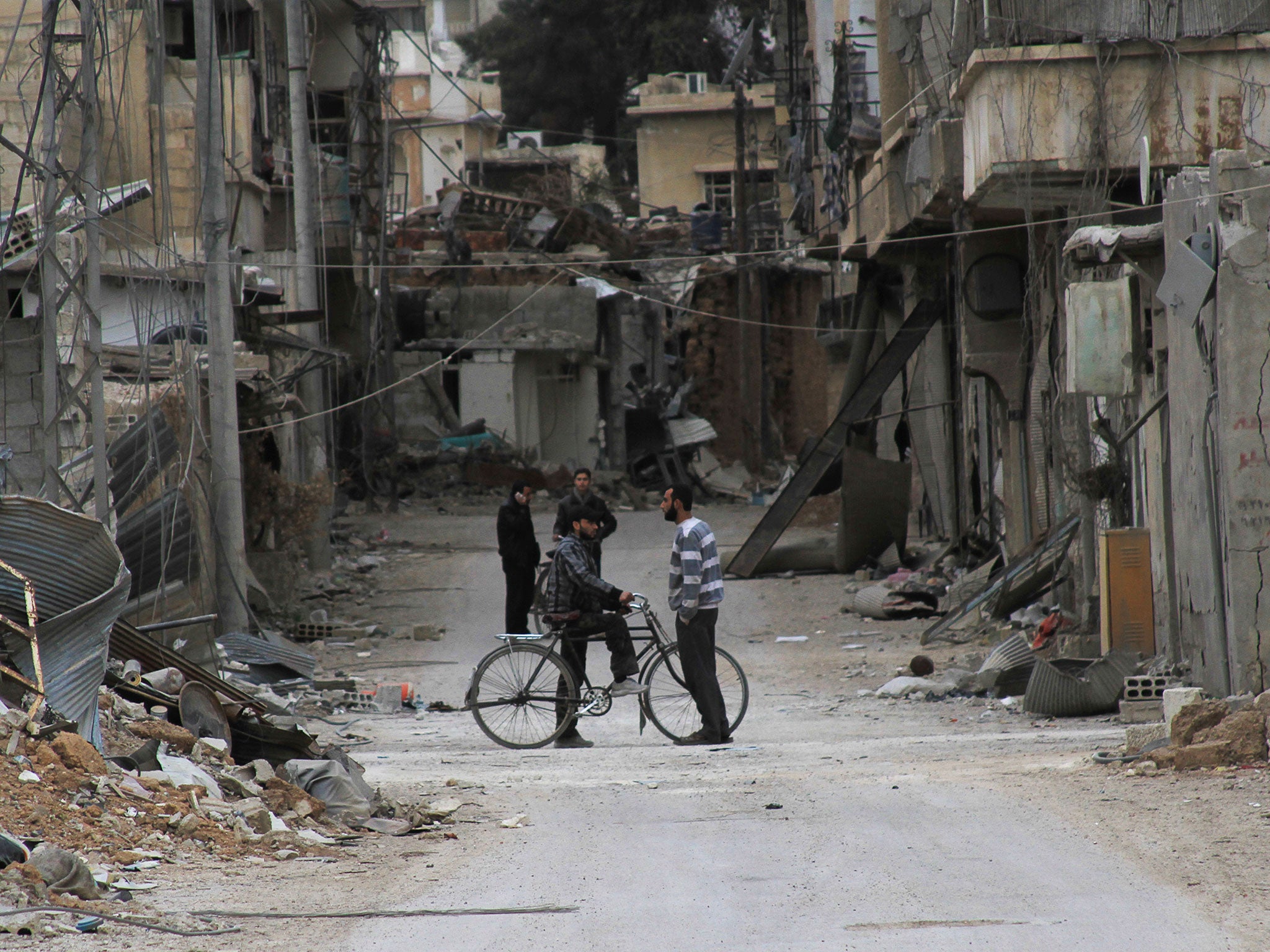 Men chat near buildings damaged by what activists said was shelling by forces loyal to Syria's President Bashar al-Assad in Daraya, near Damascus 2 February, 2014