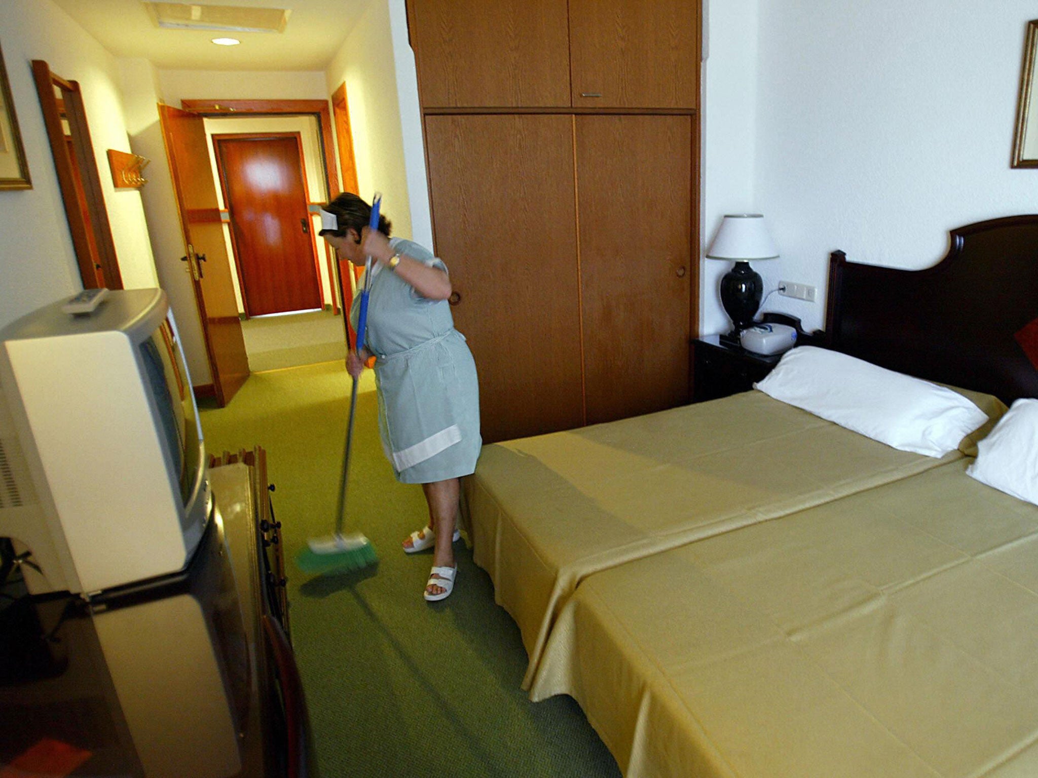 A hotel maid cleans a room