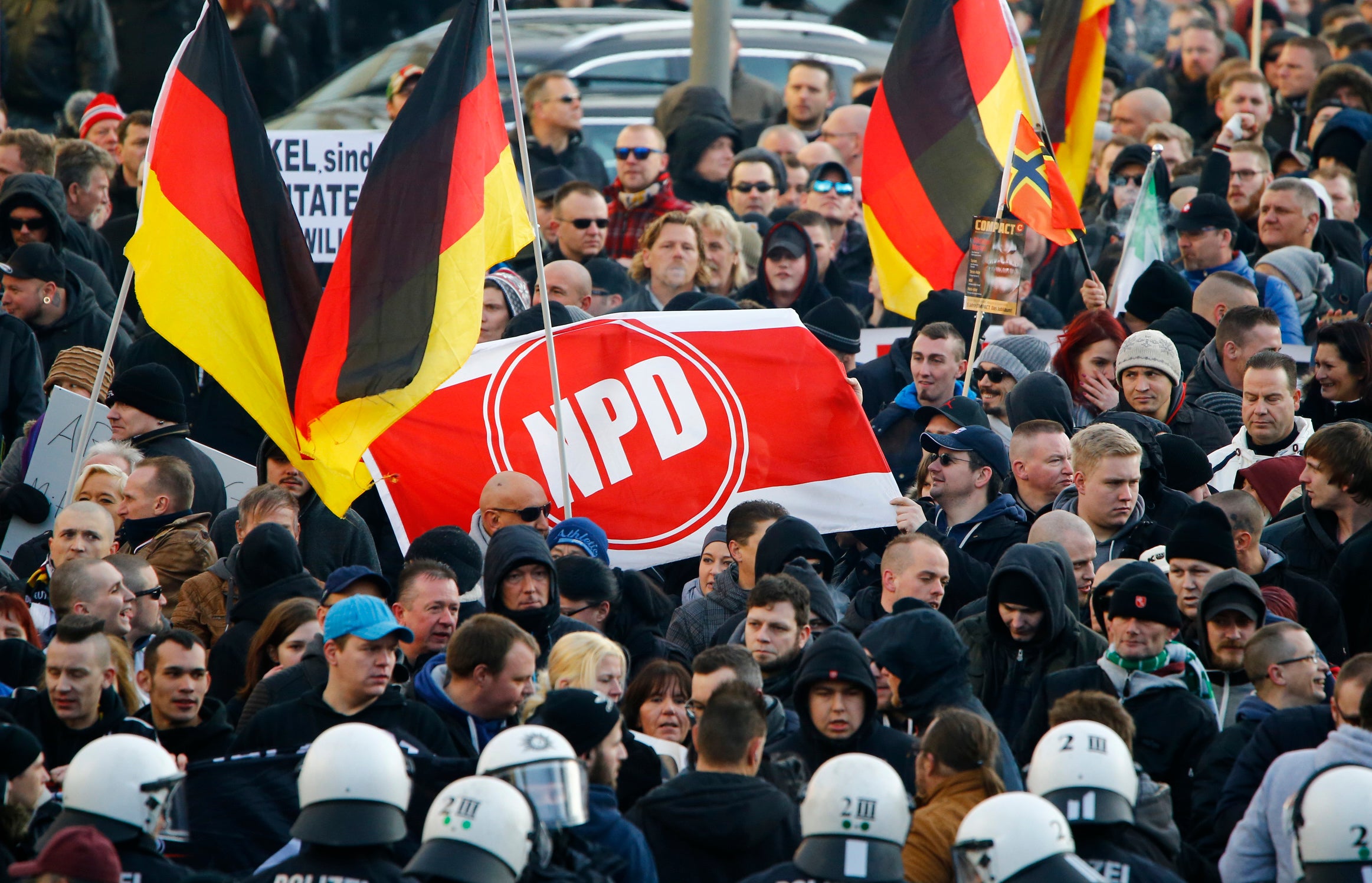 Supporters of anti-immigration right-wing movement PEGIDA (hold up a banner with the logo of the far-right National Democratic Party (NPD)