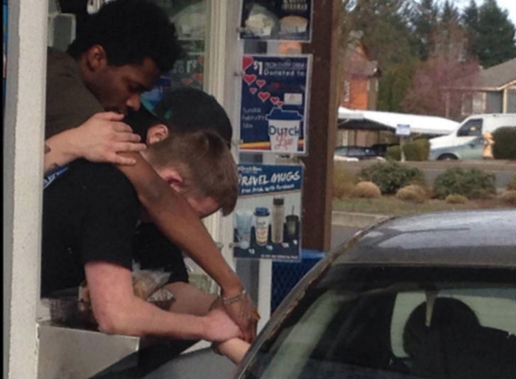 Three employees clasp the woman's hand as she drives by to pick up a coffee