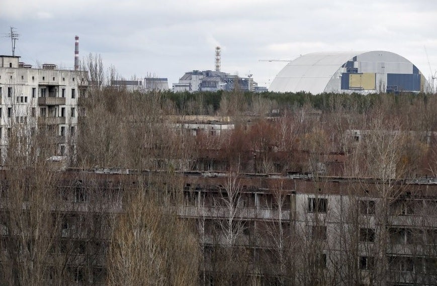 A containment shelter for the damaged fourth reactor, left, and the new safe confinement structure, right, at the Chernobyl power plant seen from Pripyat