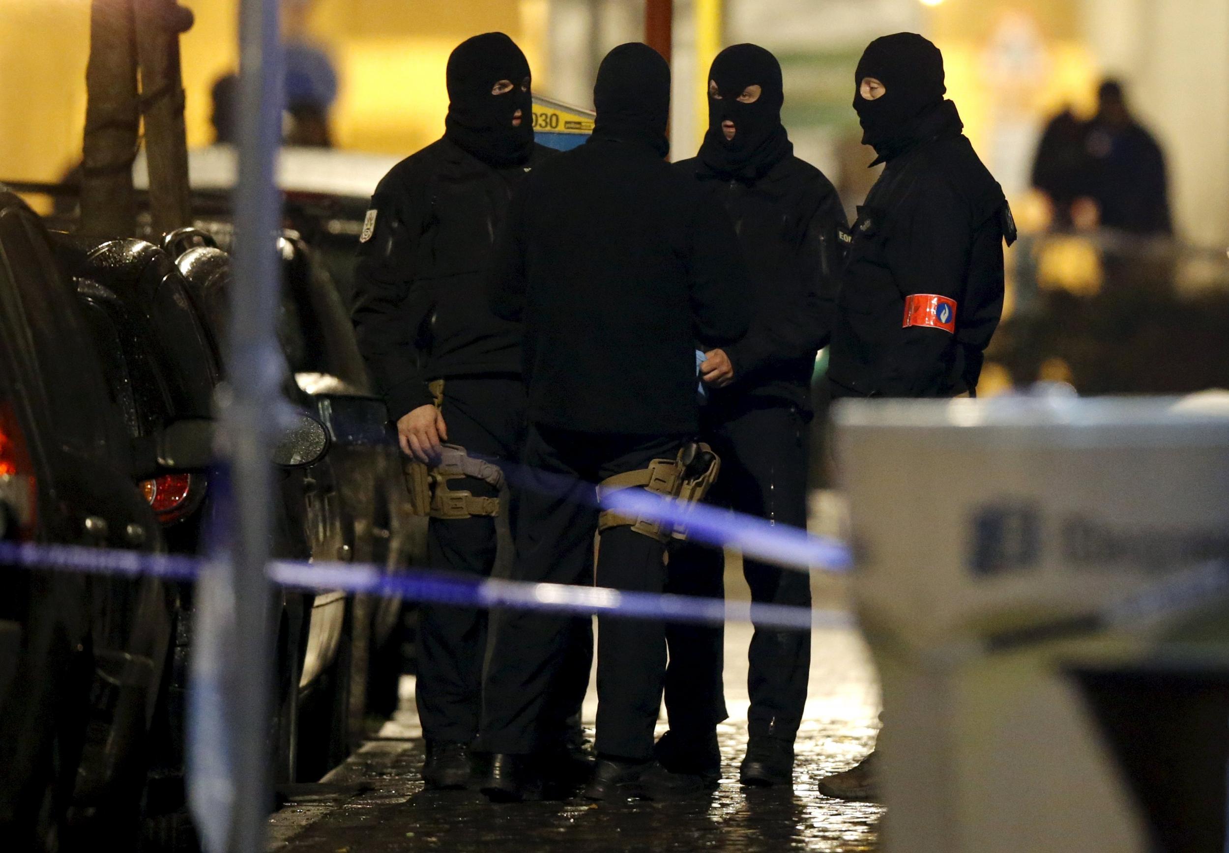 Masked Belgian police secure the entrance to a building in Schaerbeek