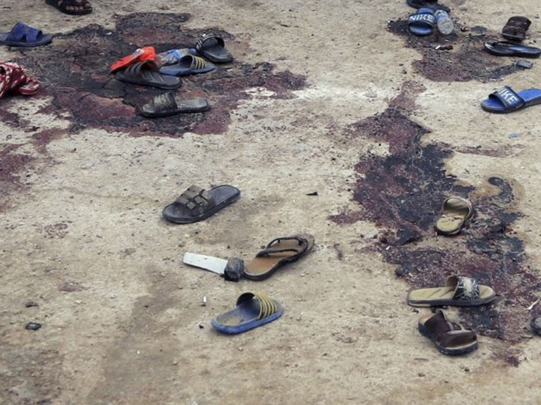 Blood stains are seen on the ground as people inspect the aftermath of a suicide bombing in Iskandariya