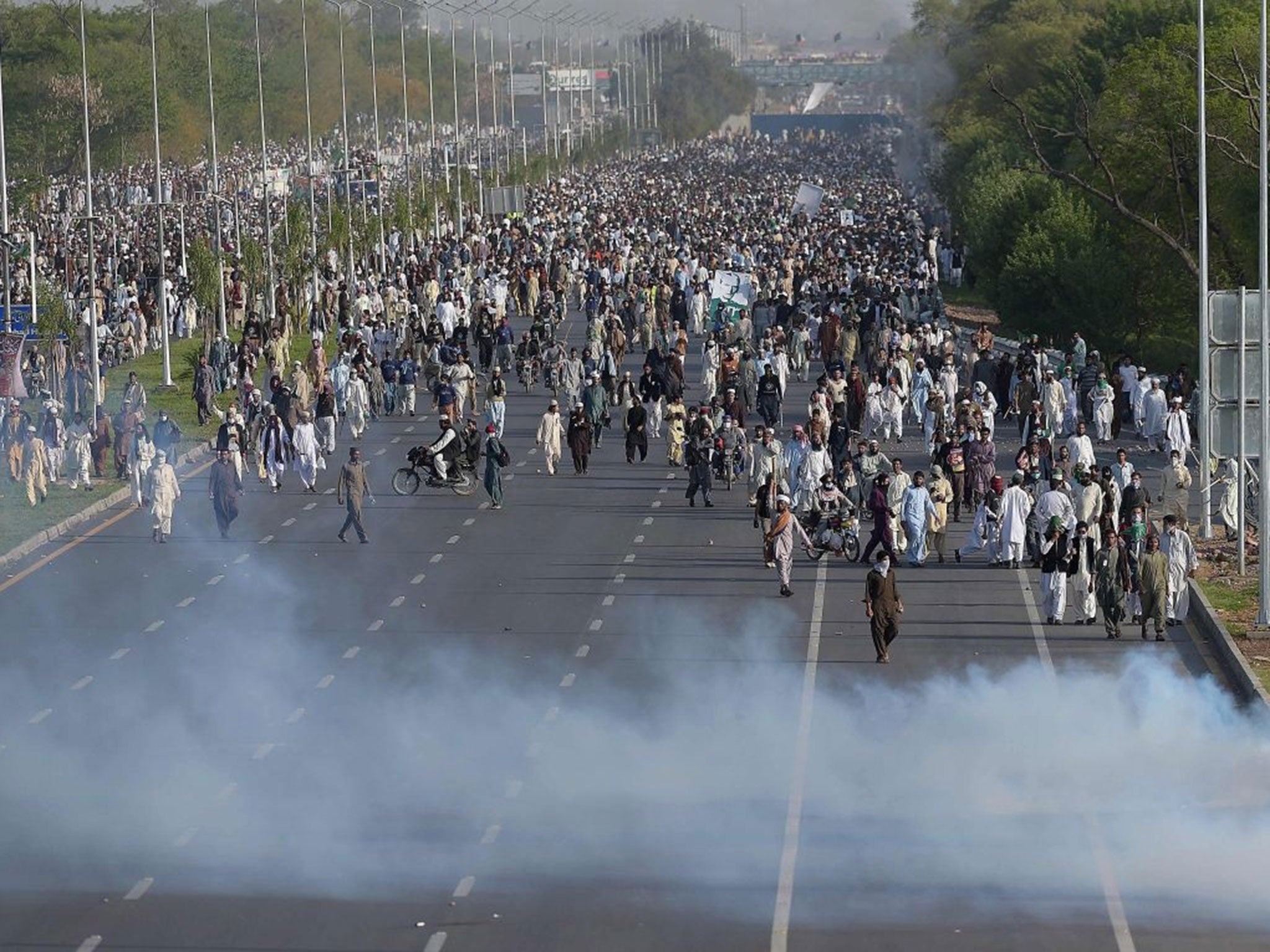 Supporters of executed Islamist Mumtaz Qadri walk through tear gas fired by police officers during an anti-government protest in Islamabad on March 27, 2016