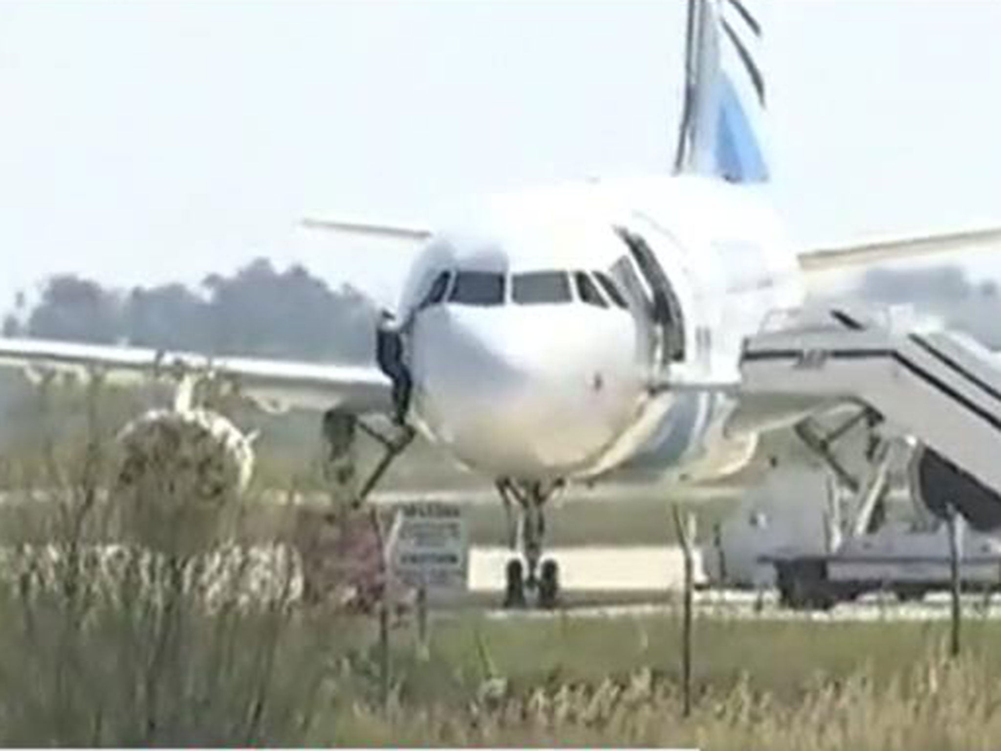 An unidentified man was filmed escaping out of the plane's cockpit window as the hostage situation continued