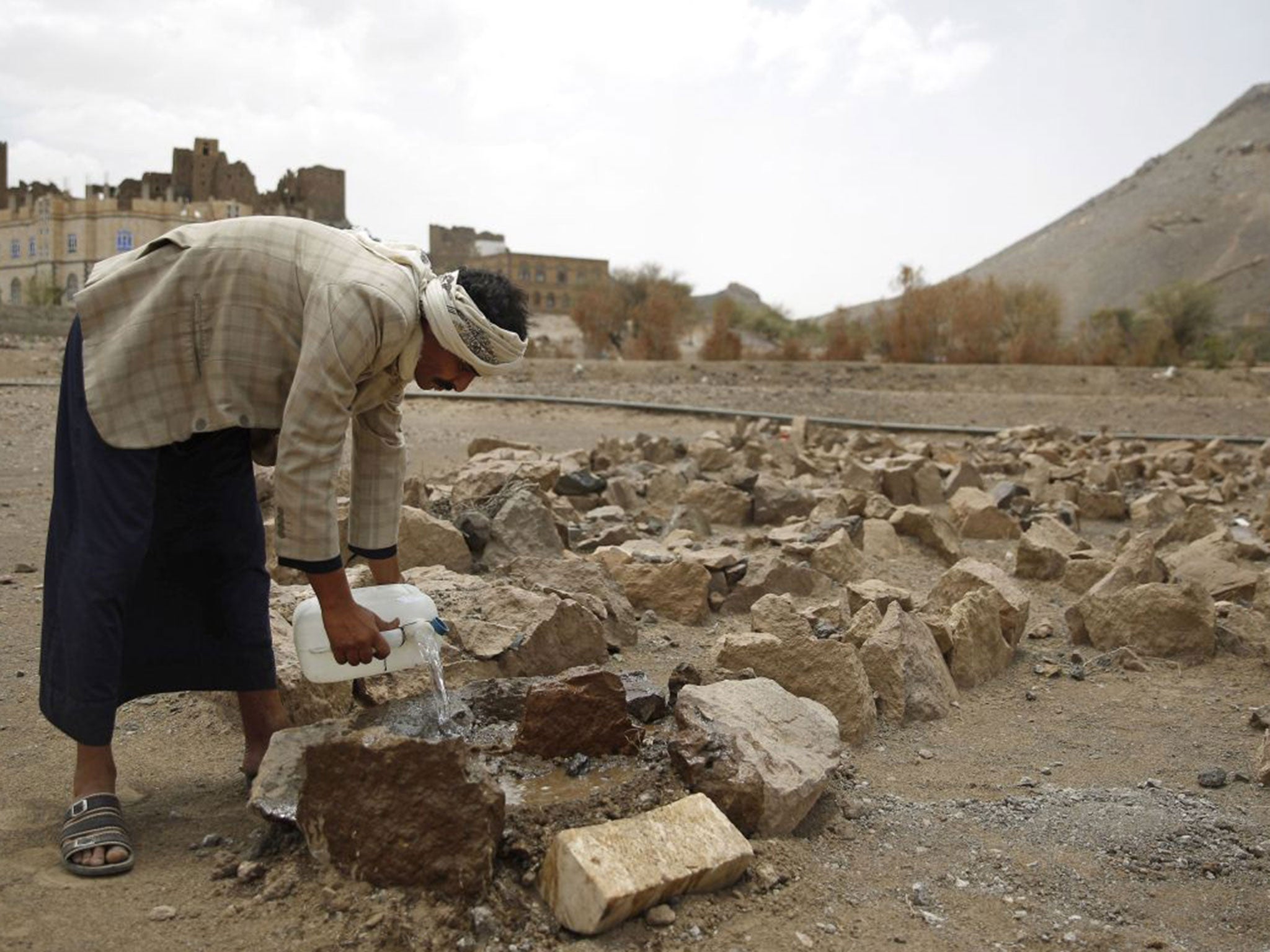 Faisal Ahmed, whose son, Udai Faisal, died of severe acute malnutrition, pours water on his grave in Hazyaz village on the southern outskirts of Sanaa, Yemen