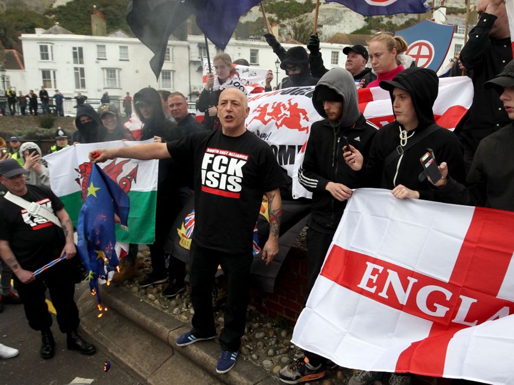 A European flag is burnt by a supporter from a group of far-right protesters, who are marching though Dover in Kent, the group are protesting against the arrival of immigrants