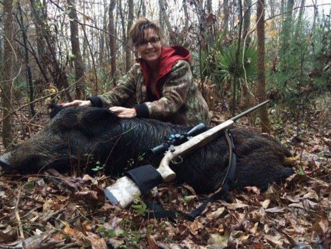 Ms Palin holds the ears of the boar and grins into the camera to encourage Trump voters