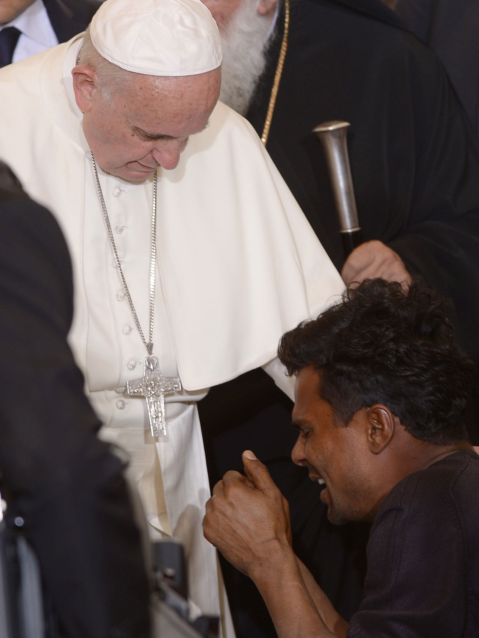 Pope Francis blesses a man kneeling in front of him as he meets migrants and refugees at the Moria detention centre