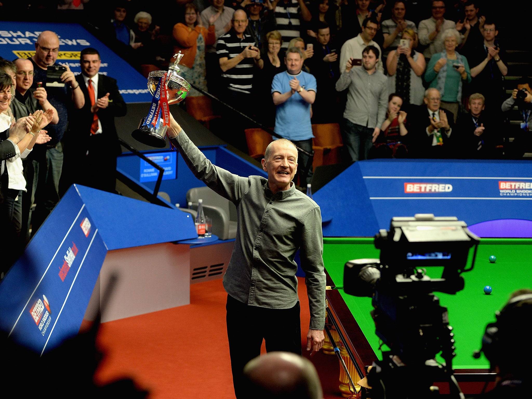 Former champion Steve Davis salutes the Crucible crowd with the World Snooker Championship trophy after announcing his retirement from the game