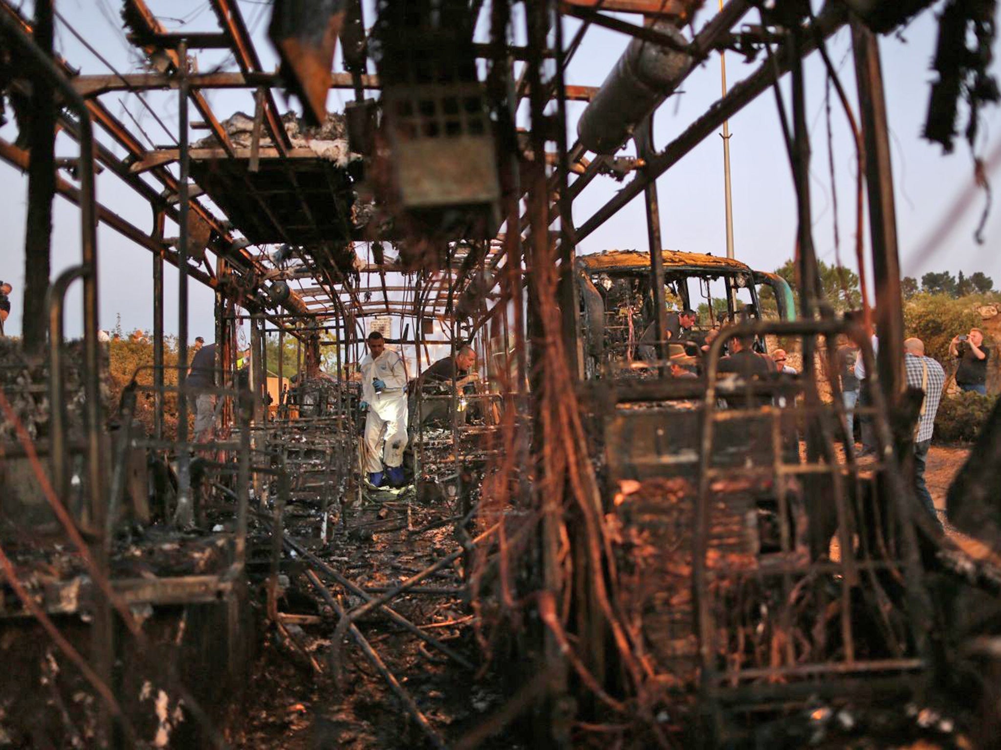 Israeli security officials search the remains of a burnt out bus following an explosion in Jerusalem