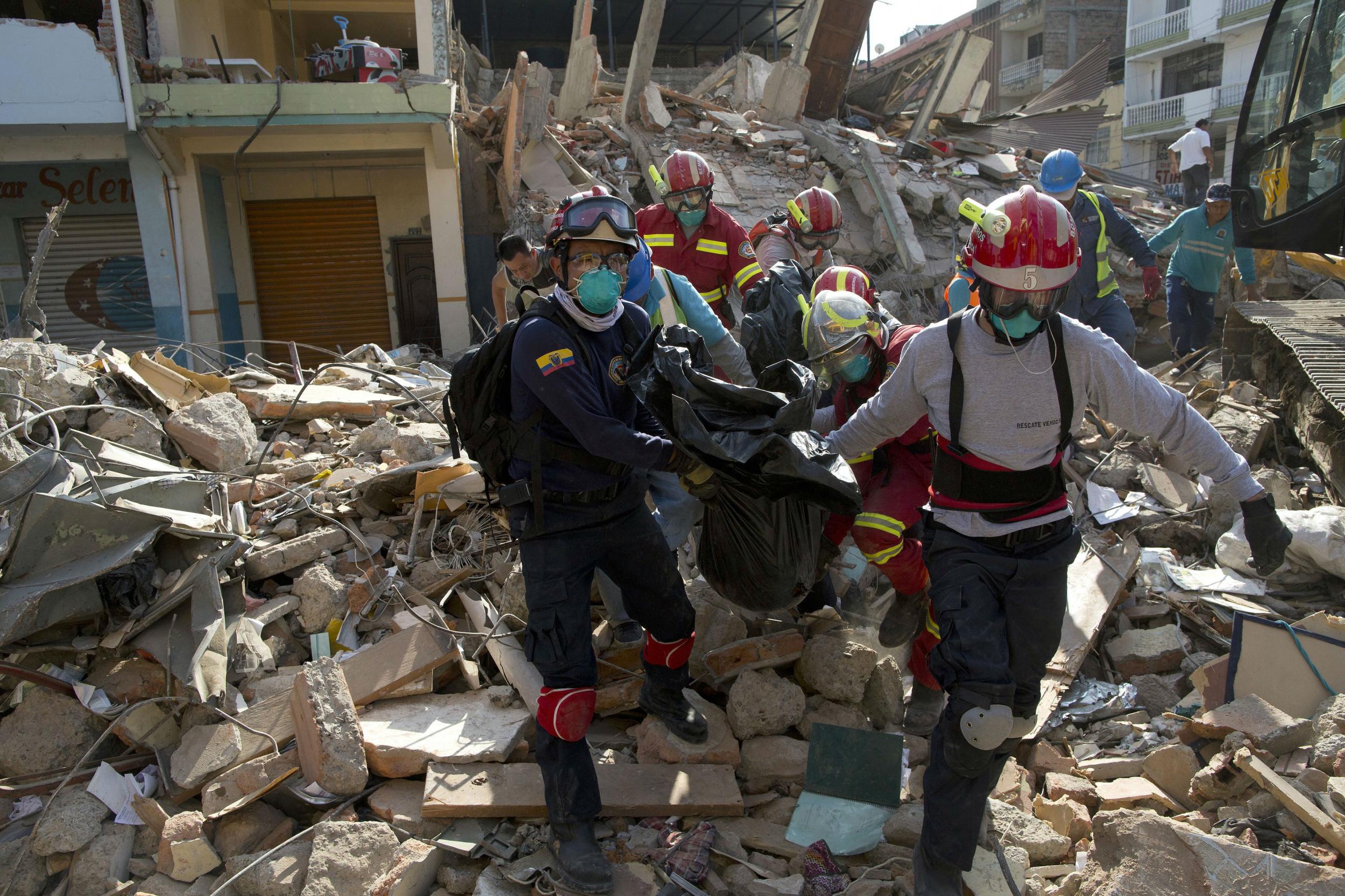 Workers remove a body from the rubble of a collapsed building