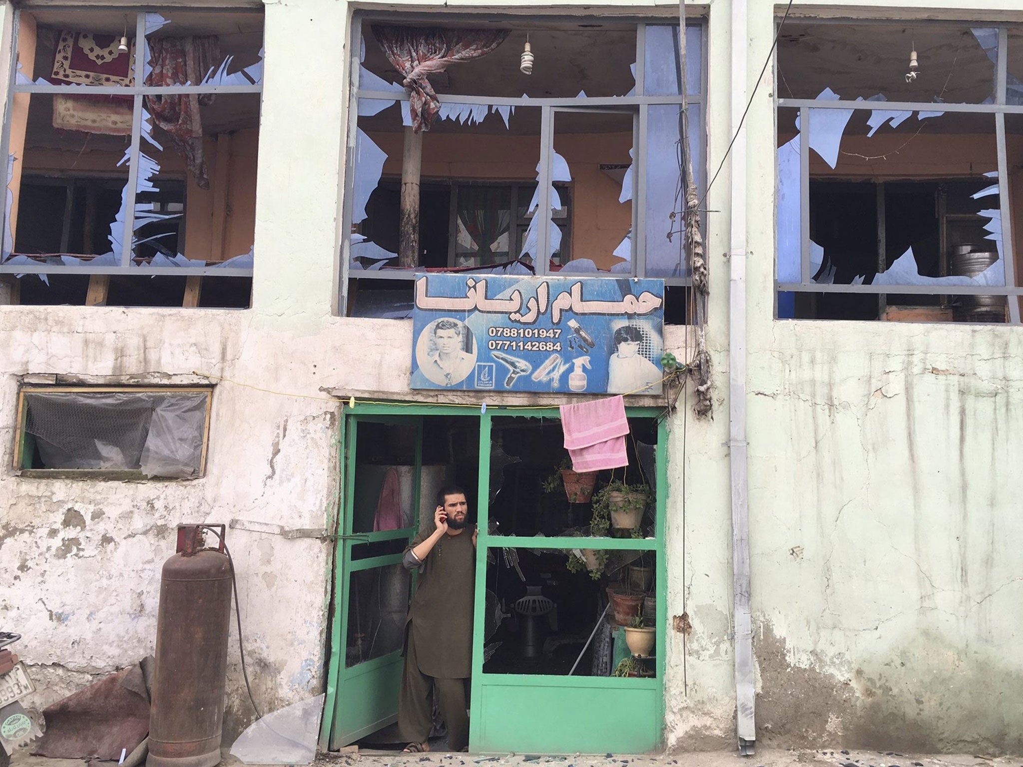 A man stands inside his damaged shop near the scene of a bomb blast in Kabul, Afghanistan, 19 April 2016