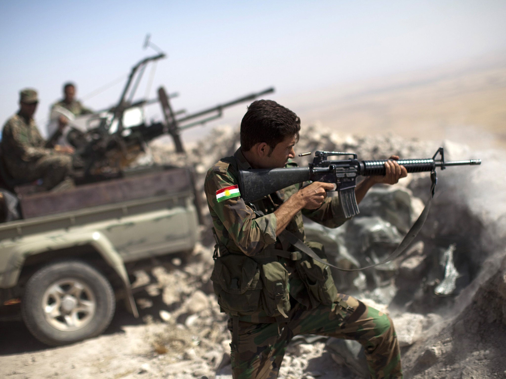 An Iraqi Kurdish Peshmerga fighter fires at Islamic-State (IS) militant positions, from his position on the top of Mount Zardak