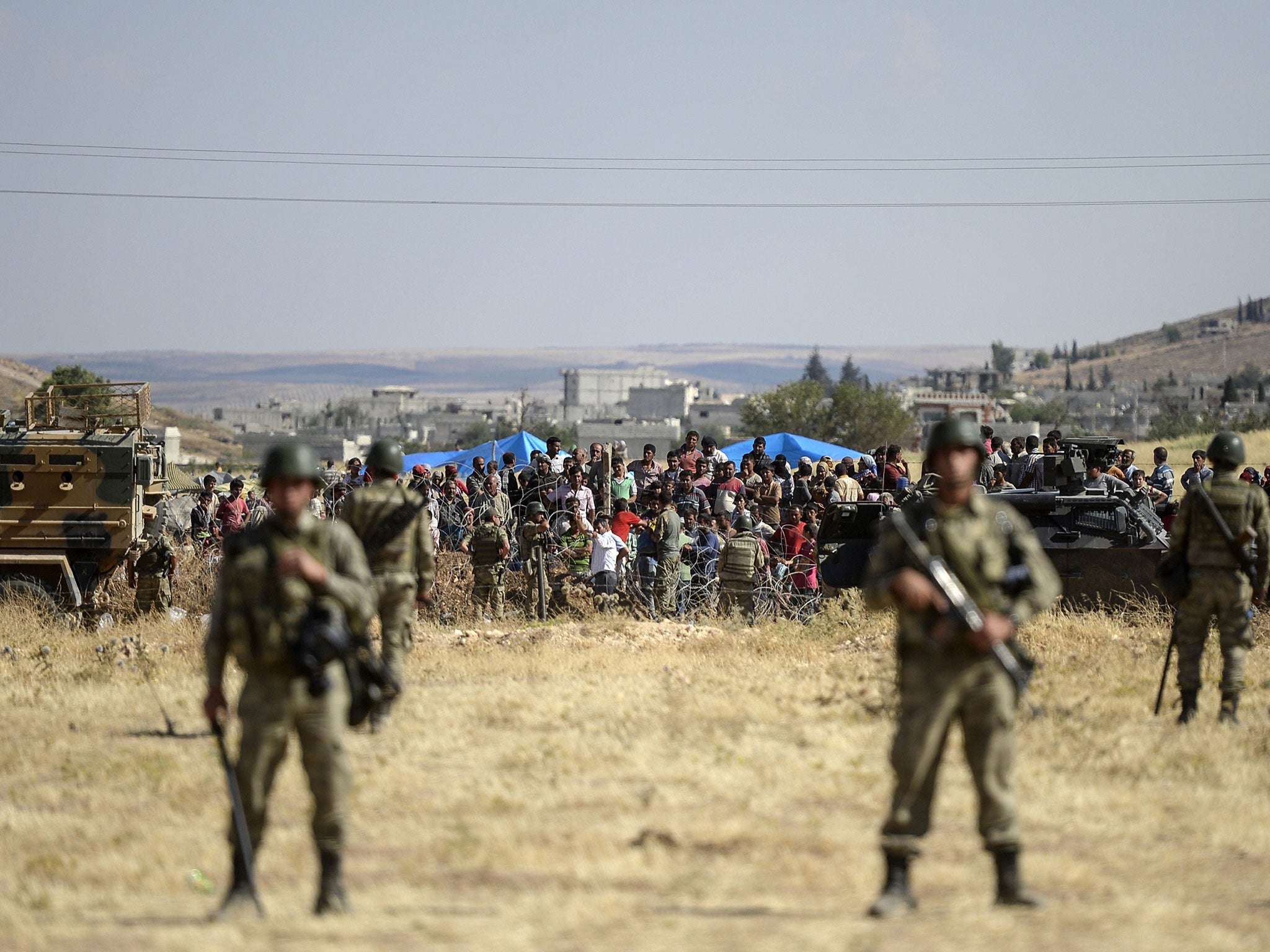 &#13;
Turkish soldiers stand guard as Kurdish people wait for their relatives on the Syrian border on June 26, 2015 &#13;