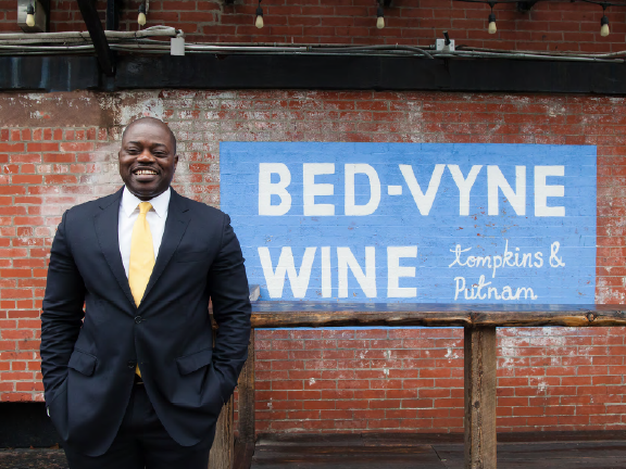 Rotimi Akinnuoye, owner of a Bedford-Stuyvesant wine shop who says Airbnb guests boost his business Airbnb