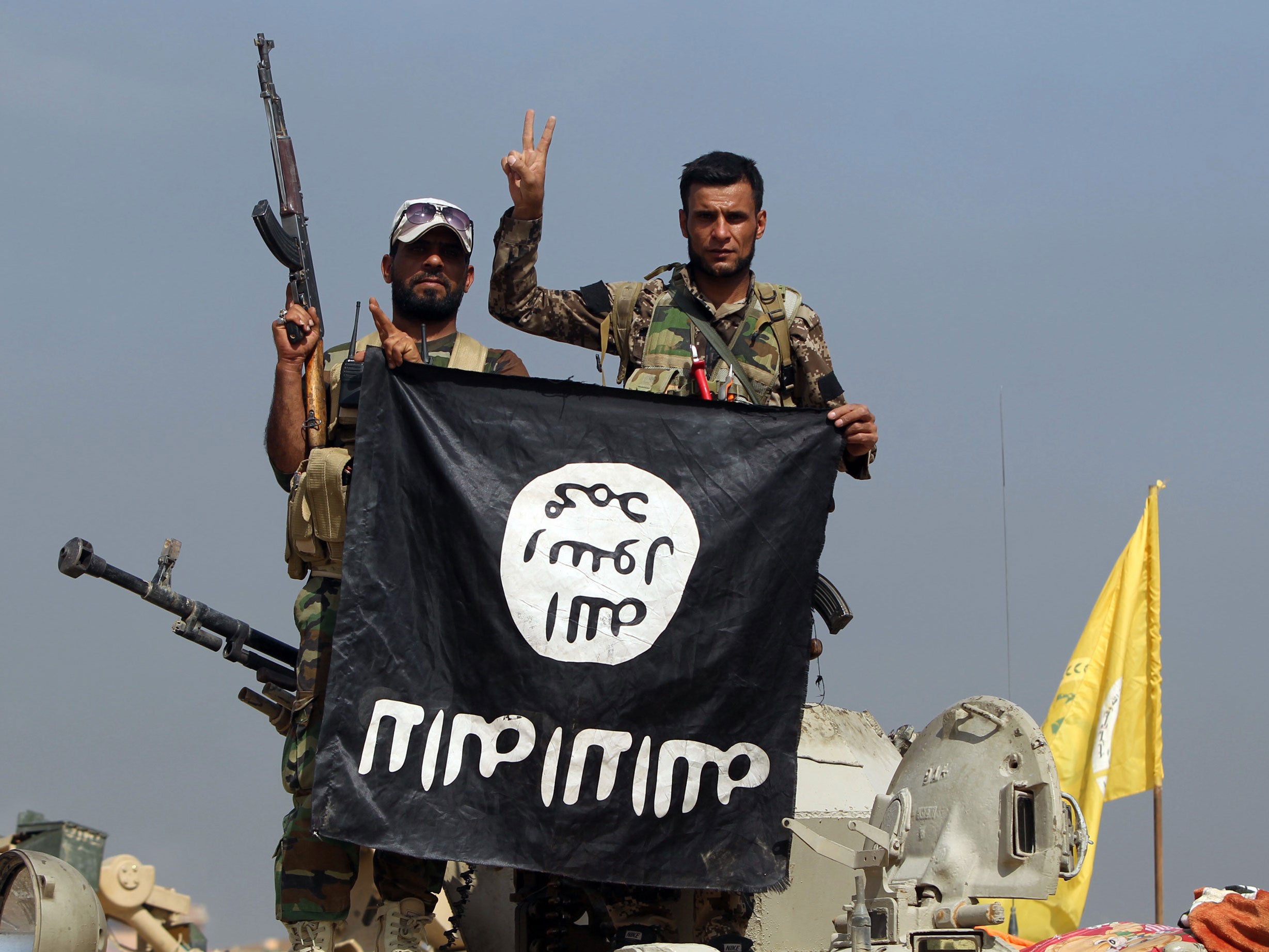 Iraqi Shiite fighters hold a captured Isis flag upside-down after an October 2015 operation