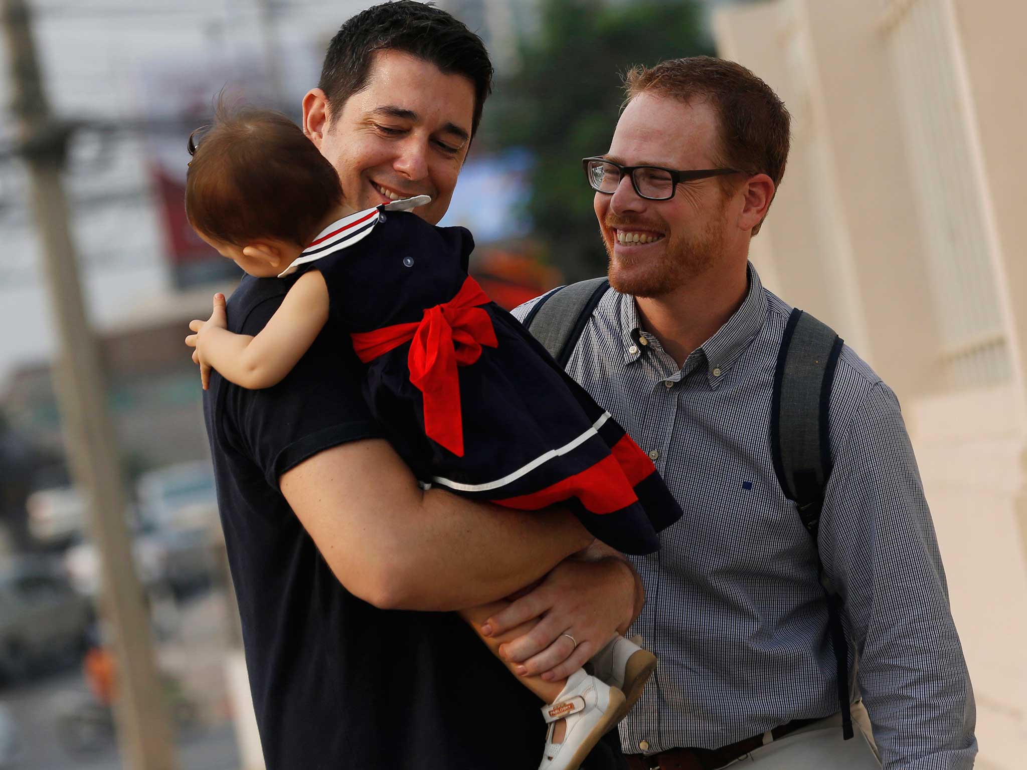 American Gordon Lake (L) and Spaniard Manuel Santos walk with their baby Carmen at the Central Juvenile and Family Court in Bangkok, Thailand