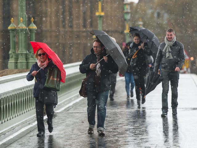 Pedestrians experience a brief snow shower on Westminster Bridge, in central London