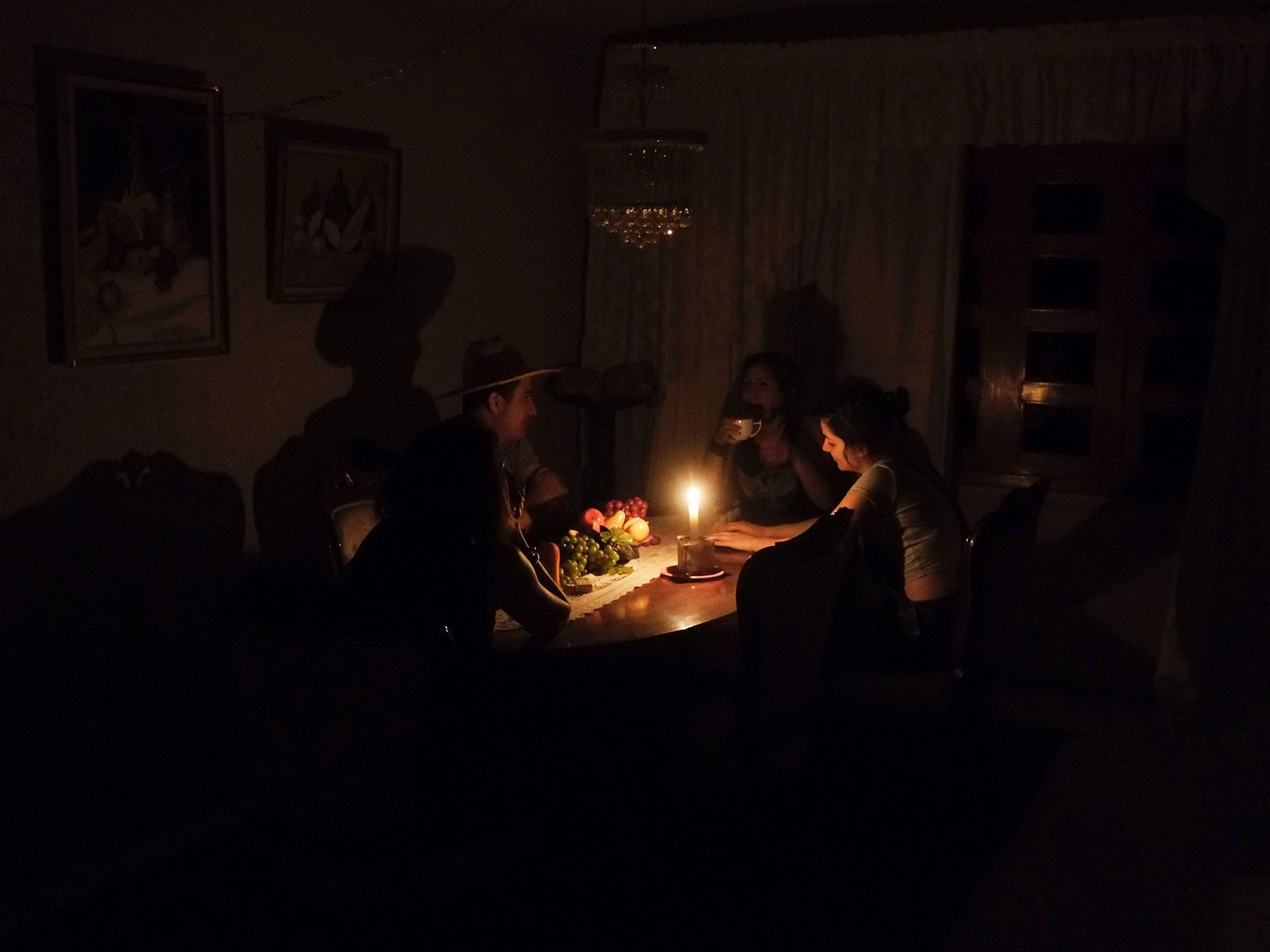 A family sit at a candle lit table during power outages in the state of Barinas, 600 km west of Caracas on April 25, 2016.