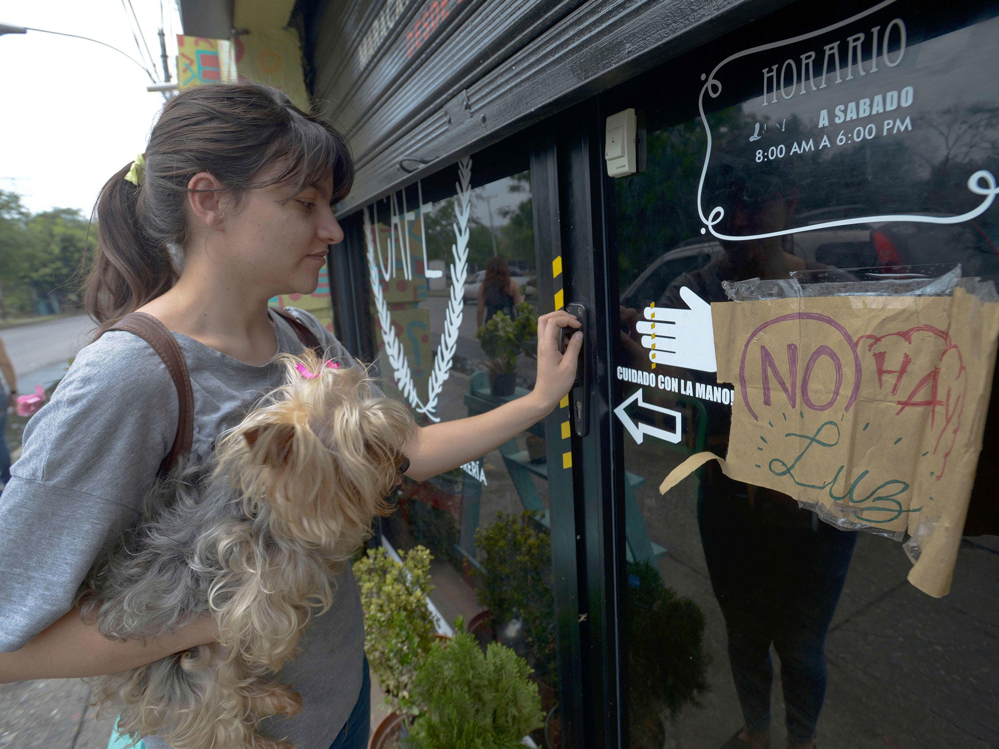 A young woman tries to enter a cafe, closed due to a power cut, in Maracay, Venezuela, on April 25, 2016.