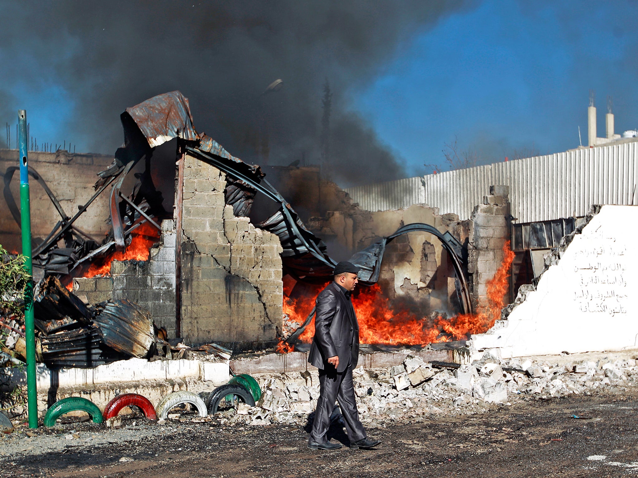 Flames rise from the ruins of a building destroyed by a Saudi air strike in Sanaa, Yemen, earlier this year