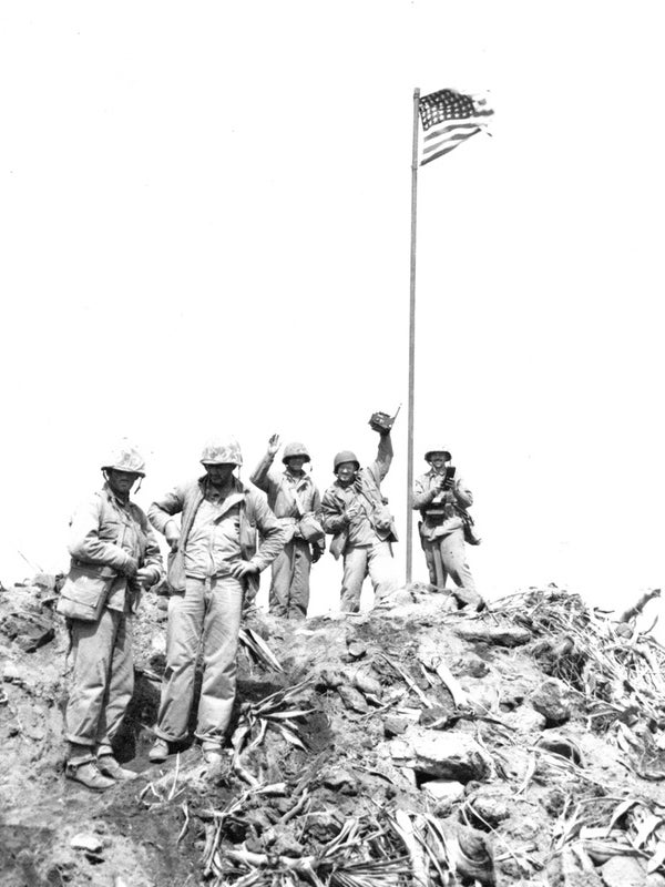 Mr Bradley (left) is shown wearing his pants with a cuff above the boot in photo taken shortly after flag was raised AP