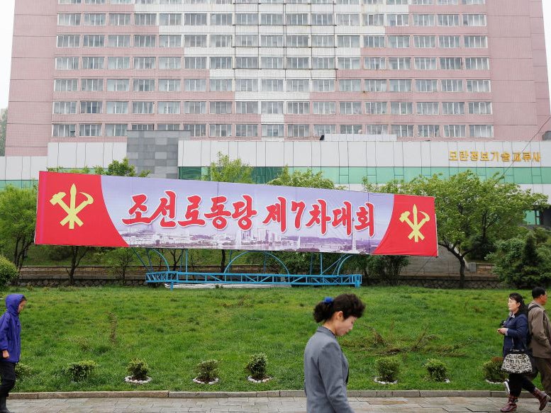 People walk in front of a banner announcing the Workers' Party of Korea (WPK) congress