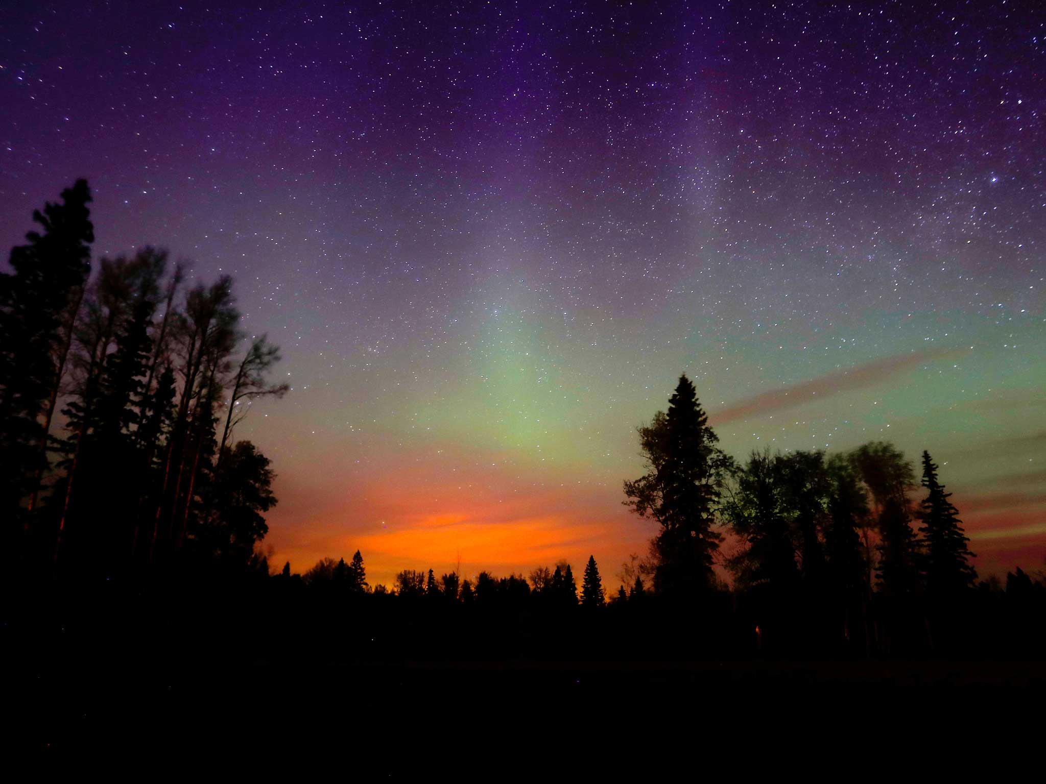 The wildfires glow underneath The Northern Lights, also known as the Aurora Borealis, near Fort McMurray, Alberta, Canada