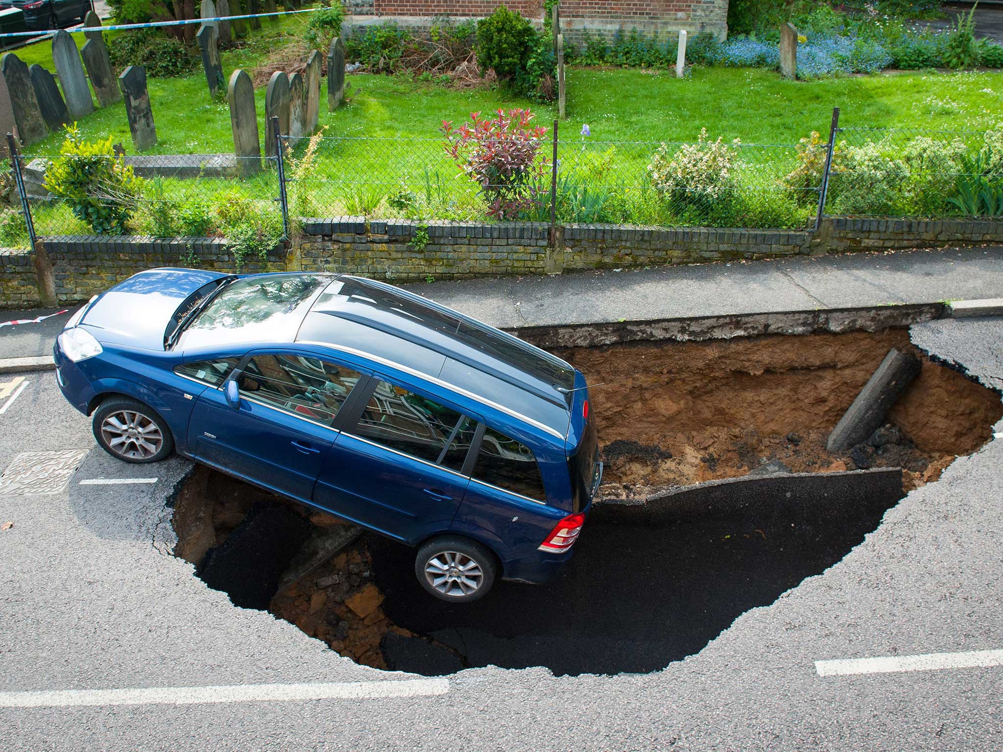 A car which has partially disappeared down a sinkhole in Woodland Terrace in Greenwich