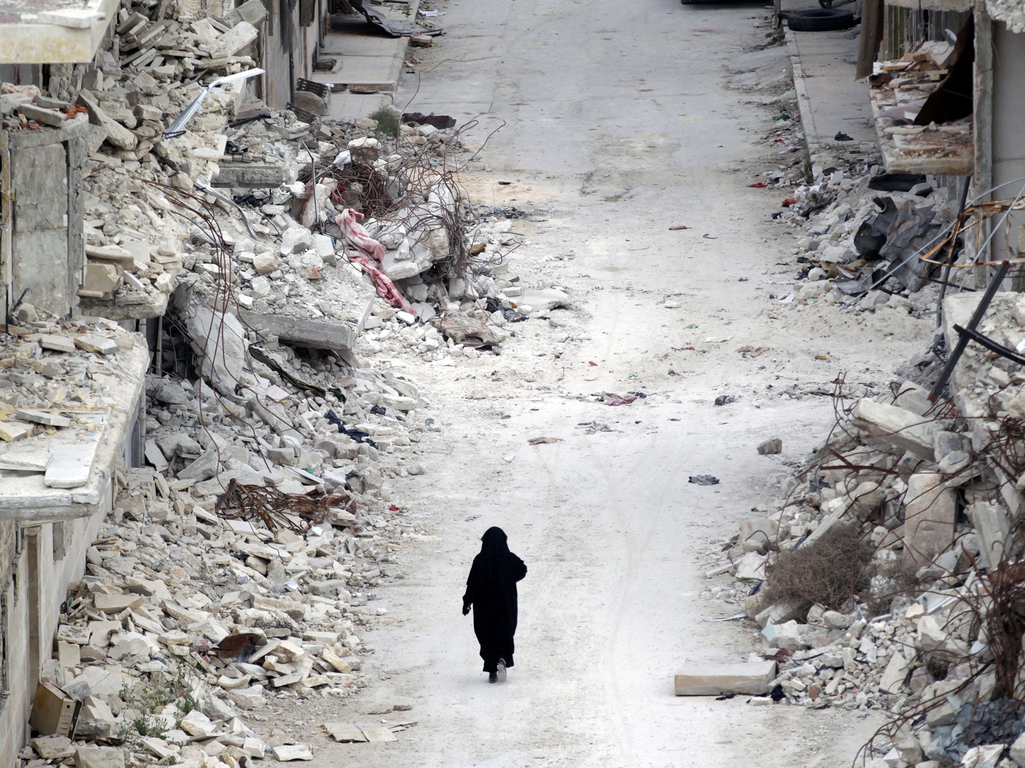 A woman walks past damaged buildings in the rebel-controlled area of Maaret al-Numan town in Idlib province