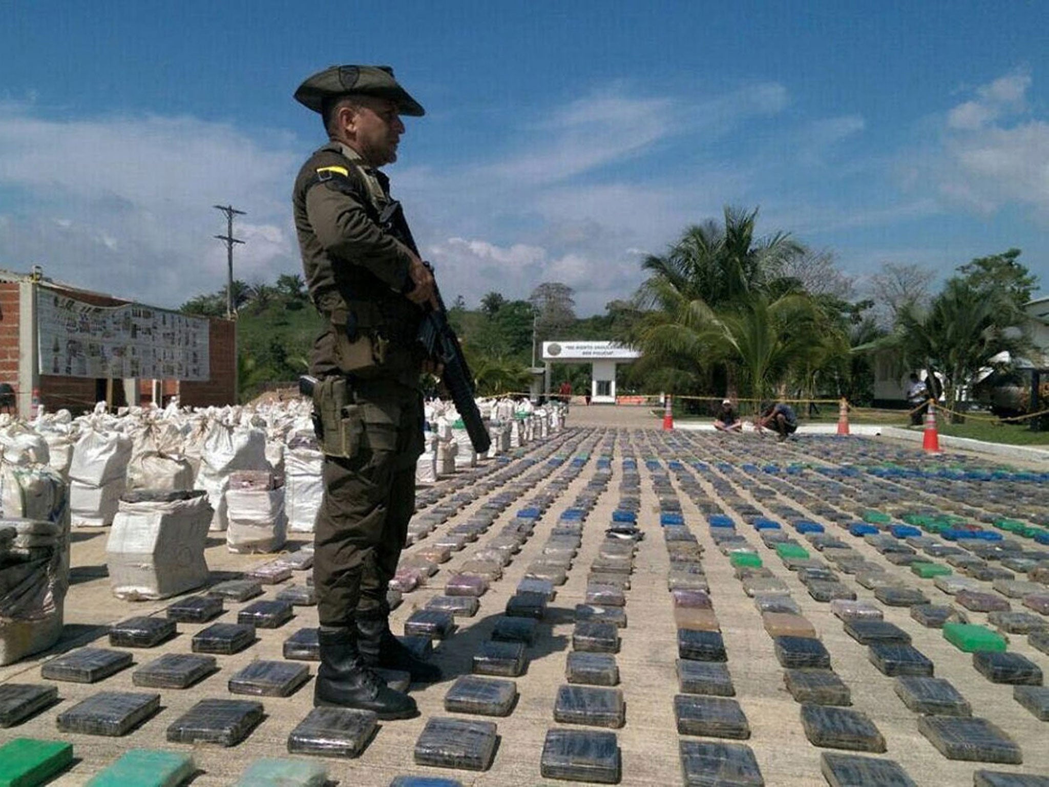 A Colombian Police officer standing guard in front of a display of confiscated packages of cocaine