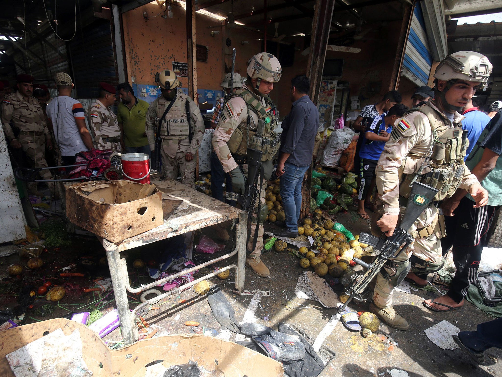 Iraqi security forces gather at the site of a suicide bombing in the Shaab area in northern Baghdad on May 17, 2016.