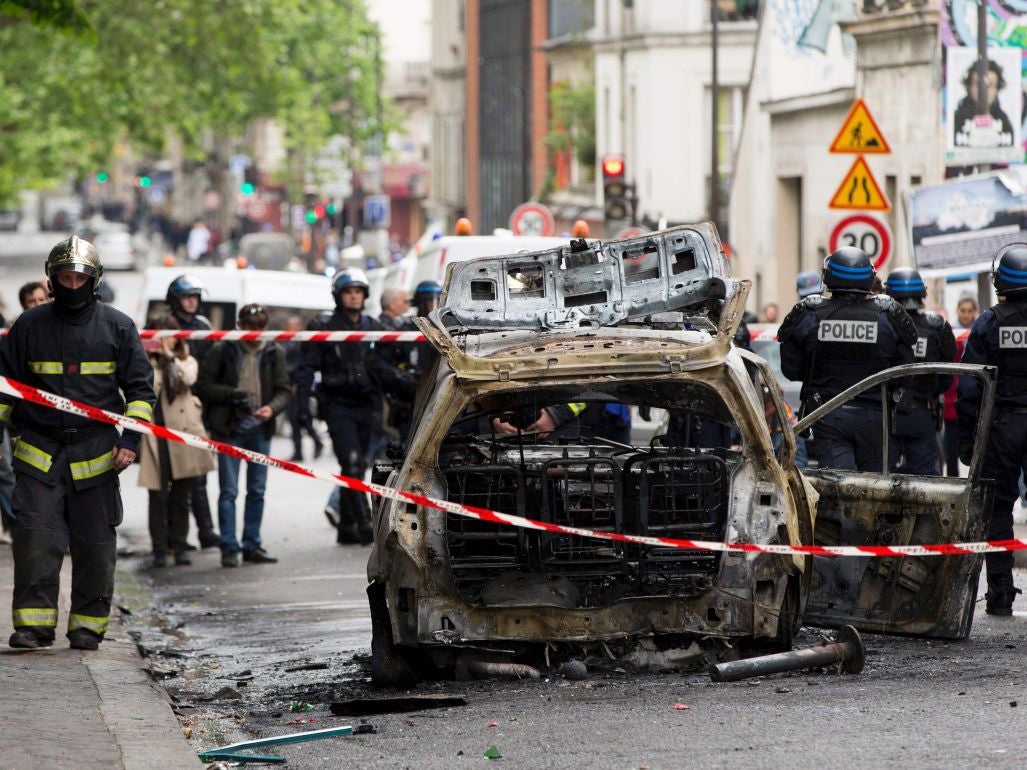 A burned-out police car near to a protest by police officers against "anti-police hatred"