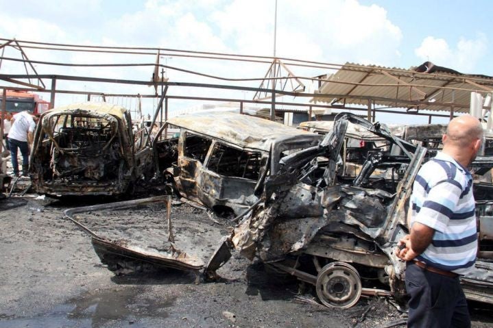 Soldiers and civilians survey the wreckage following a suicide attack in Tartous on 23 May