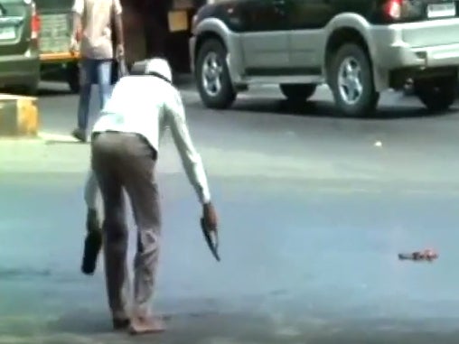 A man becomes stuck in melting tarmac as the heat wave in India continues