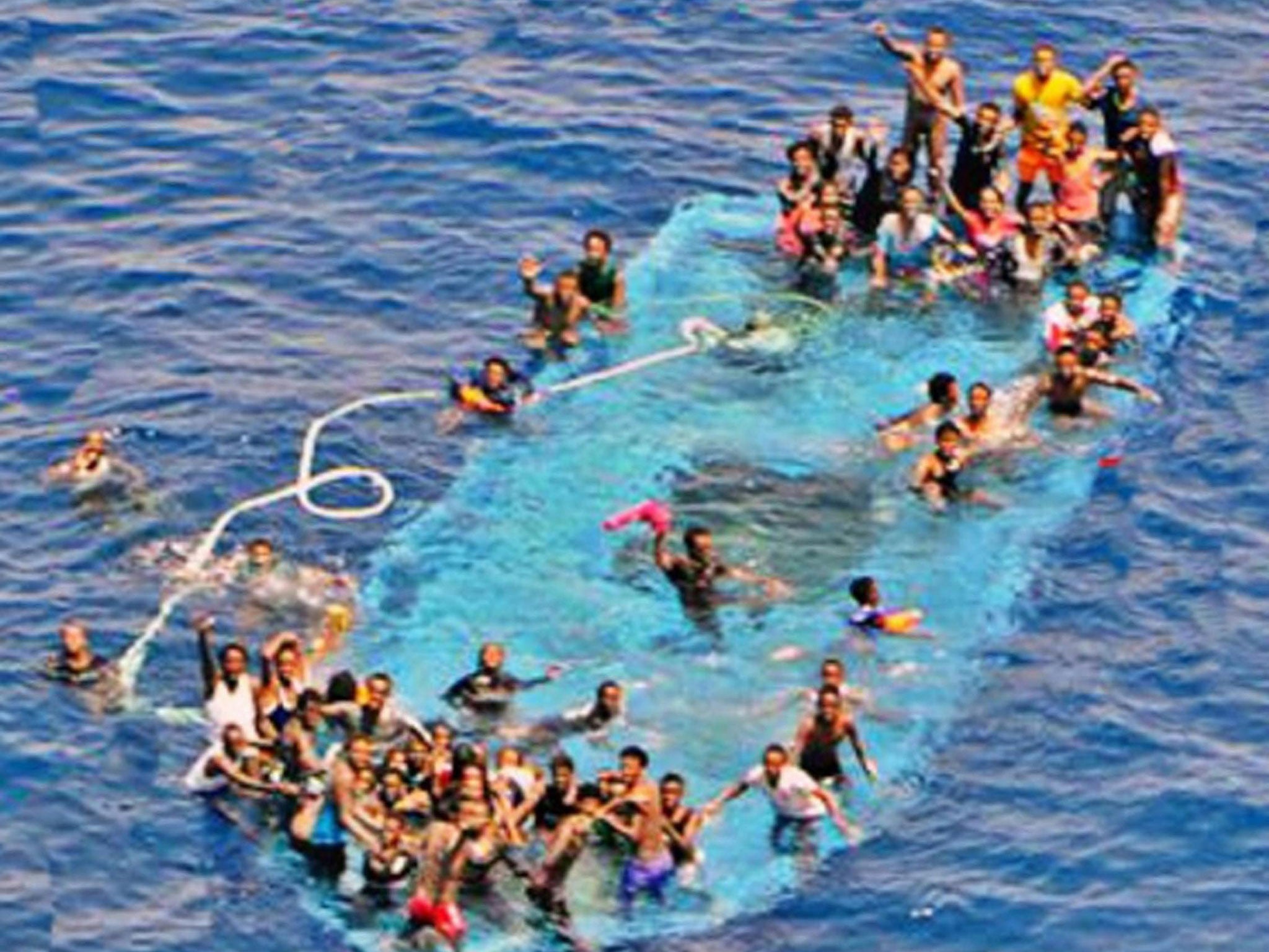 A handout picture released by the European Union Naval Force - Mediterranean (Eunavformed) on 26 May 2016 shows people on their overturned boat in Canal of Sicily off the Libyan coast